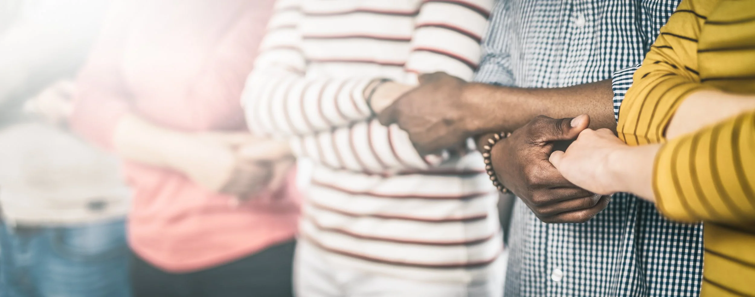 Multiple people holding hands in a support gesture.