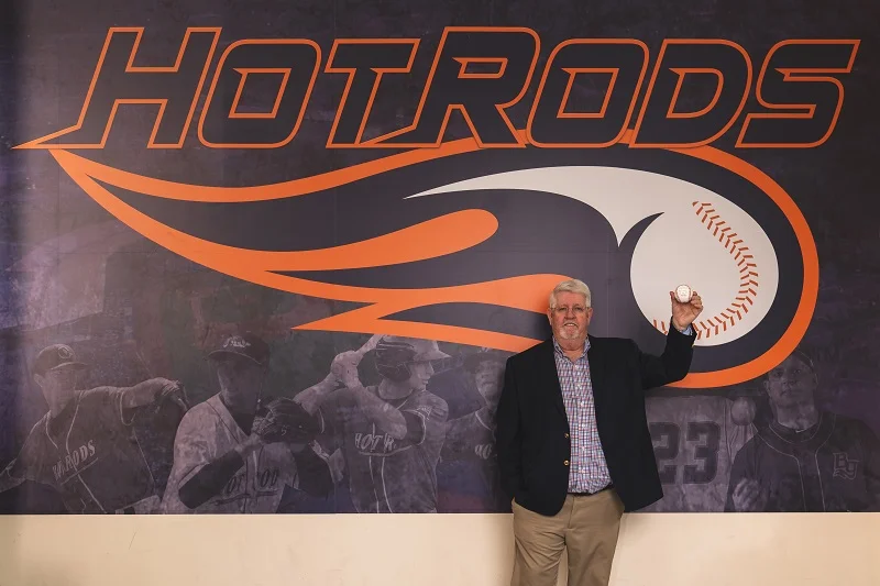 AJ holding a signed baseball in front of the Hot Rods offices.