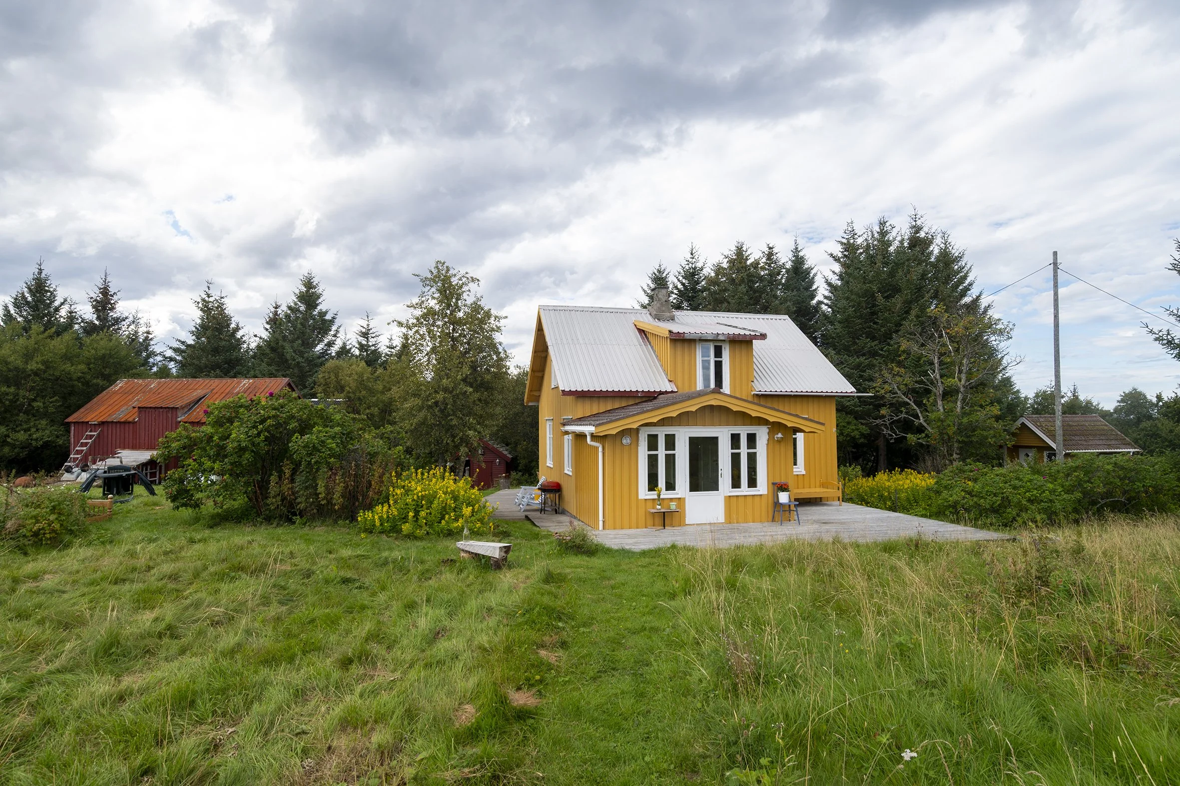 Småbruket Hubroheimen - gult lite hus i skogbrynet