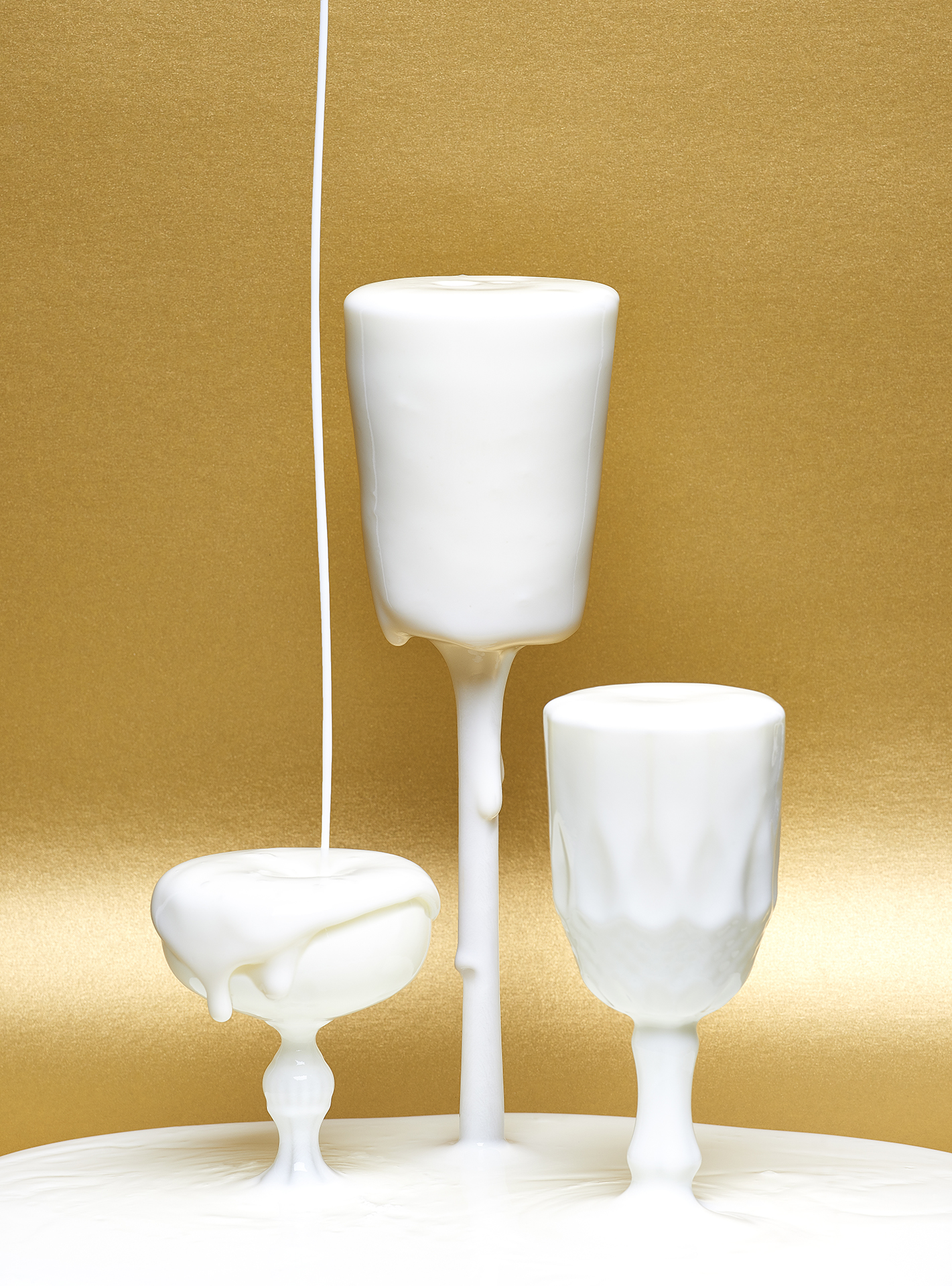  Yoghurt being dropped in glasses with a golden background 