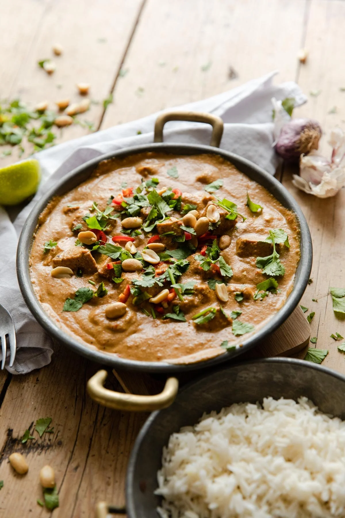 Tofu satay curry in a dish topped with peanuts, chillies, and coriander 