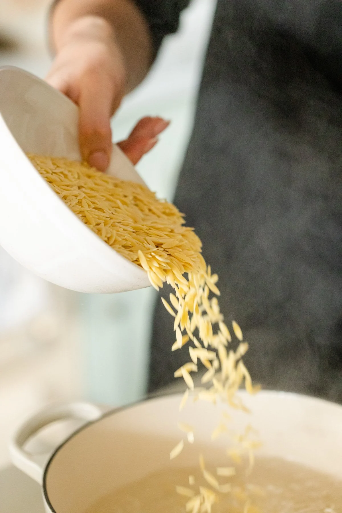 Pouring orzo into saucepan Pouring orzo into saucepan