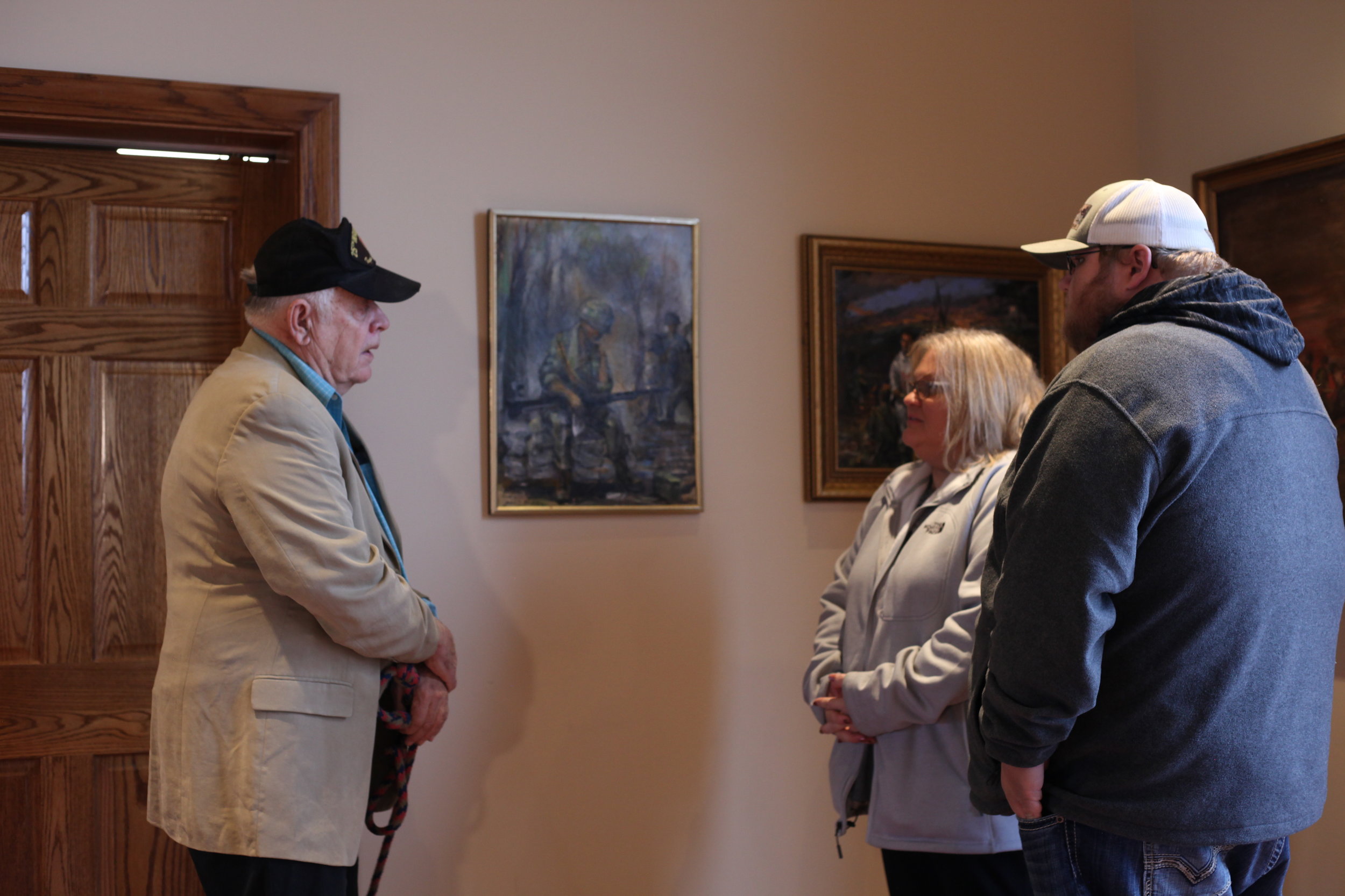 Jim Nelson showing one of his original paintings, featuring a portrait of John Gibson, to Gibson’s daughter and grandson. On display at Missouri’s National Veterans Memorial in Perryville, MO. Photo: Colin Elkins