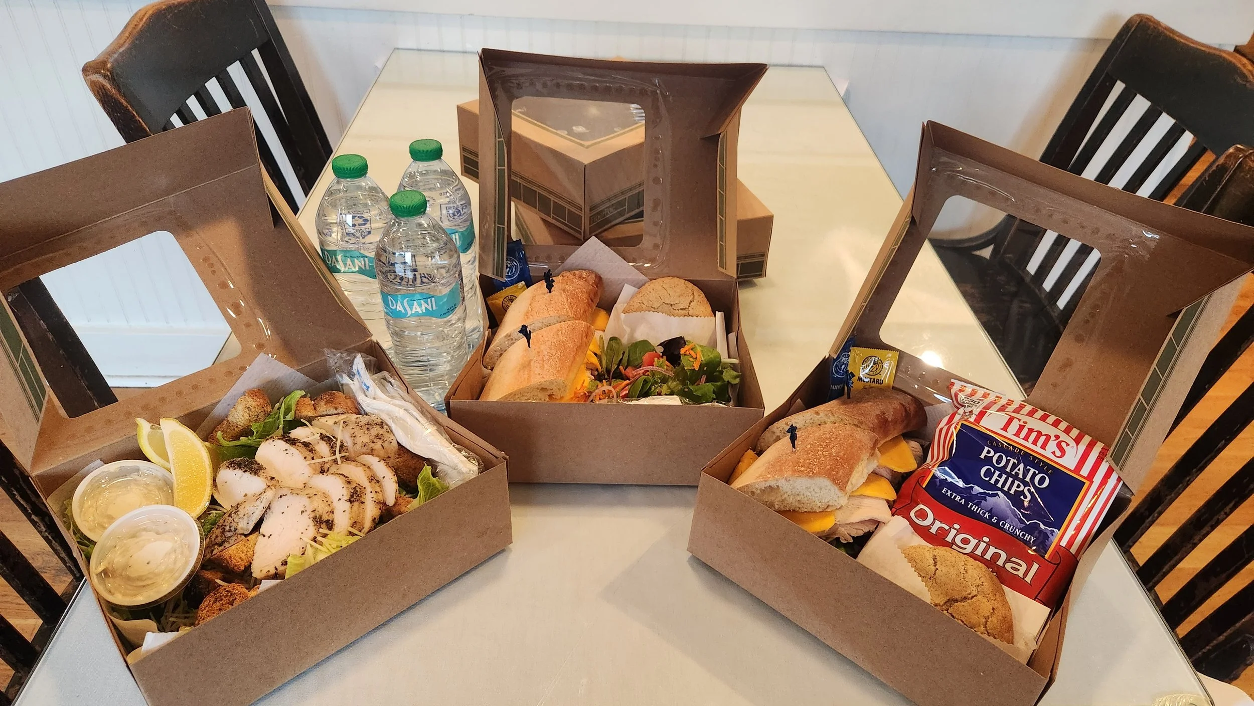 A photo of three boxed lunches, with sandwiches and salads available for catering.
