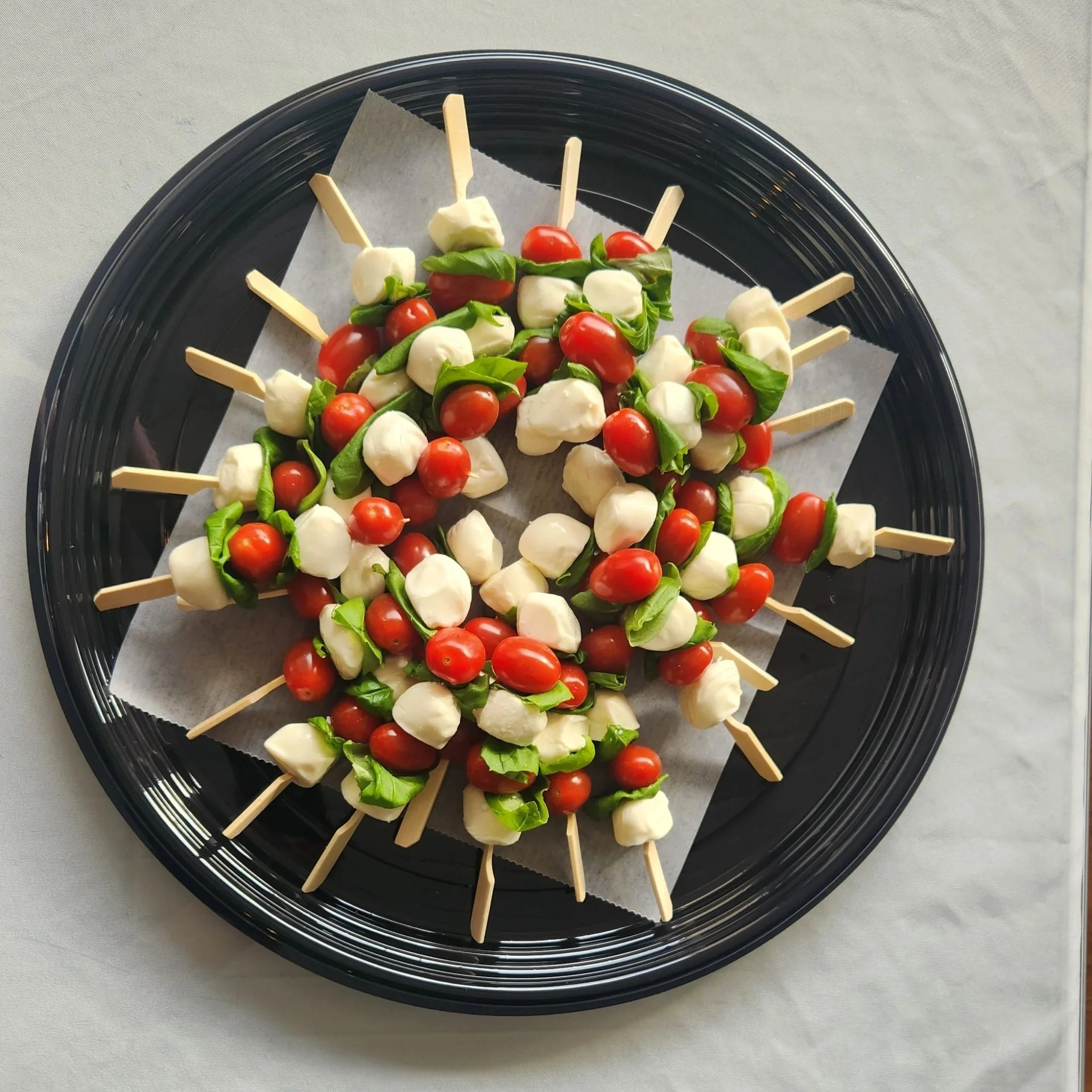 A photo of caprese skewers with cherry tomatoes, mozzarella balls and fresh basil