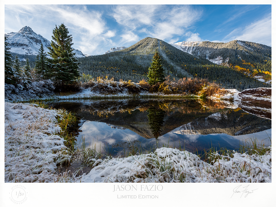 Fresh overnight snow surrounding a small spring reflecting the surrounding mountains and nature