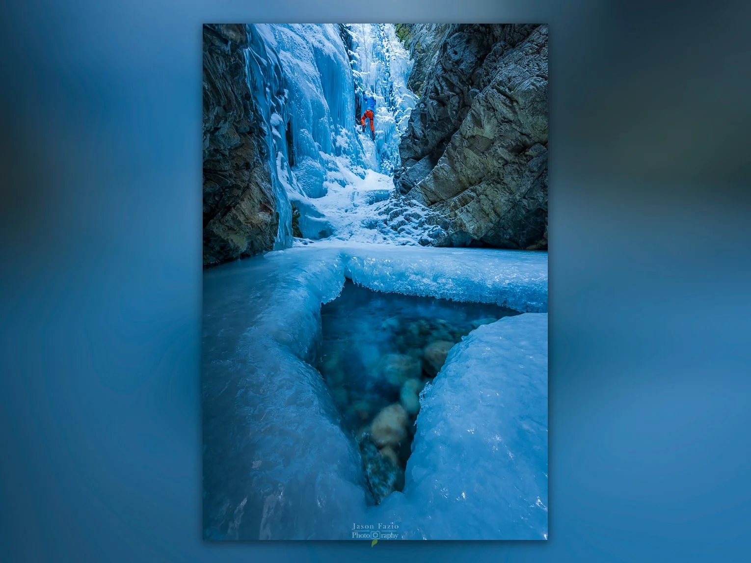 Ice climber in the background climbing a frozen Zapata Falls with an opening in the frozen creek showing the flowing waters beneath.
