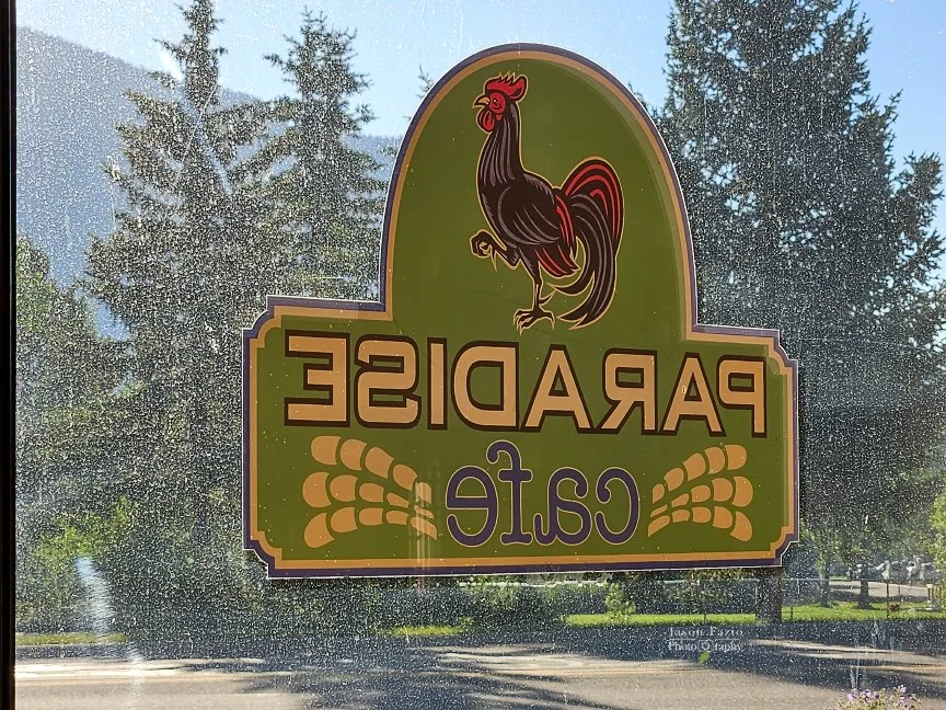 Paradise Cafe rooster logo and sign photographed through a window in Crested Butte, Colorado.