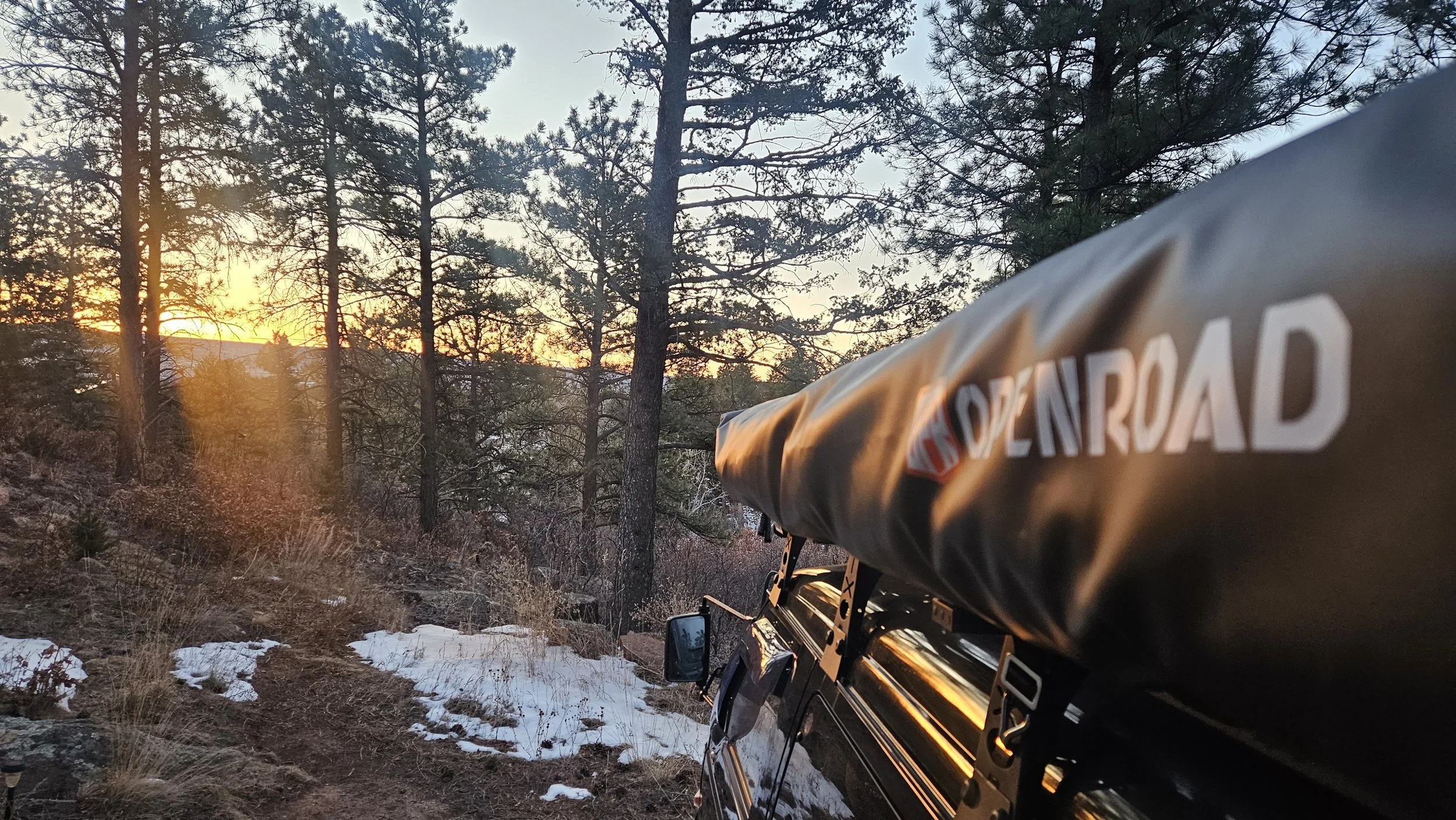 OPENROAD 270-degree Adventure Series awning packed in its cover on the passenger-side roof rack of a Mitsubishi Delica L300 at sunrise.