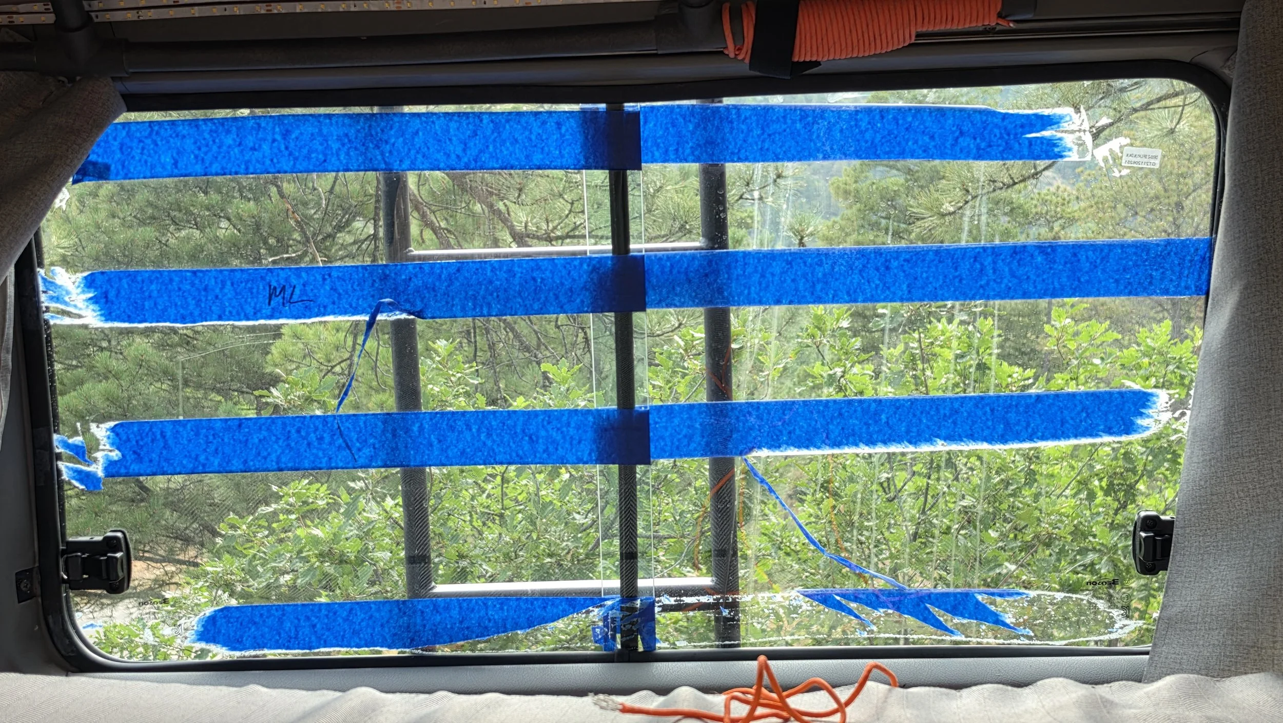 Sliding window in the Mitsubishi Delica L300, aka the Five Billion Star Hotel, covered in stuck-on painter's tape.
