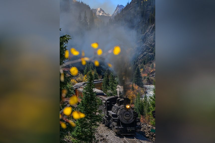 Durango and Silverton Narrow Gauge Railroad steam train traveling through autumn colors in the San Juan Mountains of Colorado.