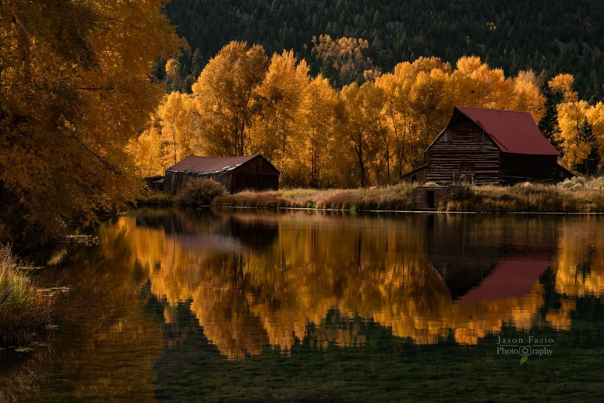 Autumn landscape with historic cabins reflected in a pond, representing landscape photography training with Jason Fazio.