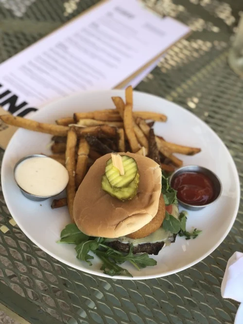 The K27 Cheeseburger: chargrilled to order, layered with Irish cheddar, onion rings, greens 7 tomato. Served with horseradish mayo and crispy french fries drizzled with truffle oil.