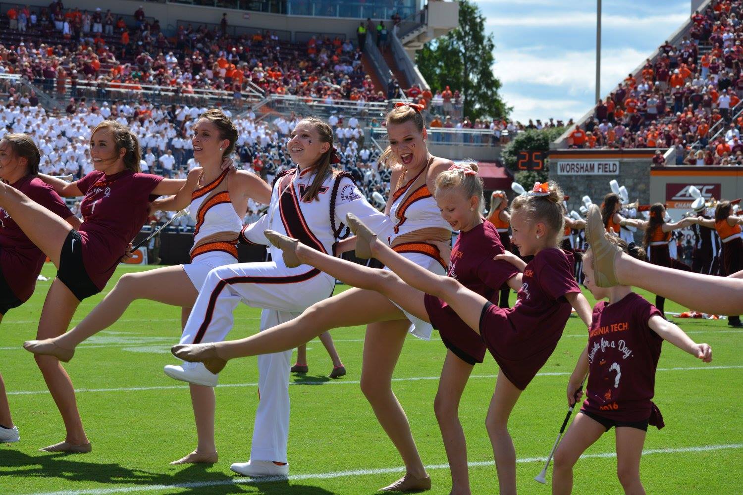 Former Drum Major Jenna Sharer, feature twirlers Kaitlyn Boyer and Serena Bronk, and lots of little twirlers for the day join us in dancing along to the Hokie Pokie during halftime; Source: Facebook