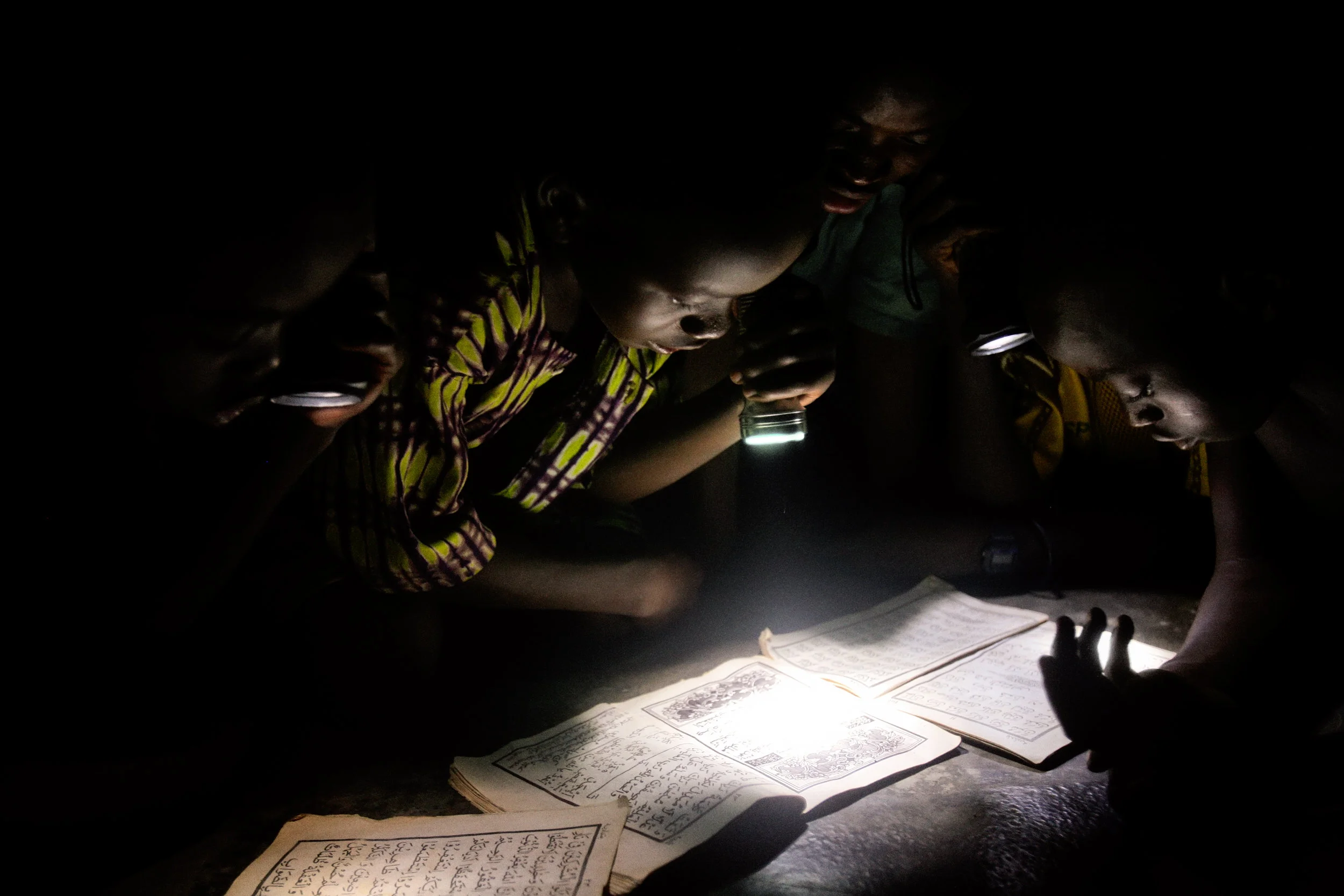 Children read the Koran by flashlight at a mosque in Wantugu, Northern Region, Ghana on May 13, 2007. Wantugu had power lines installed in 2000, but government officials failed to connect them to a power source.