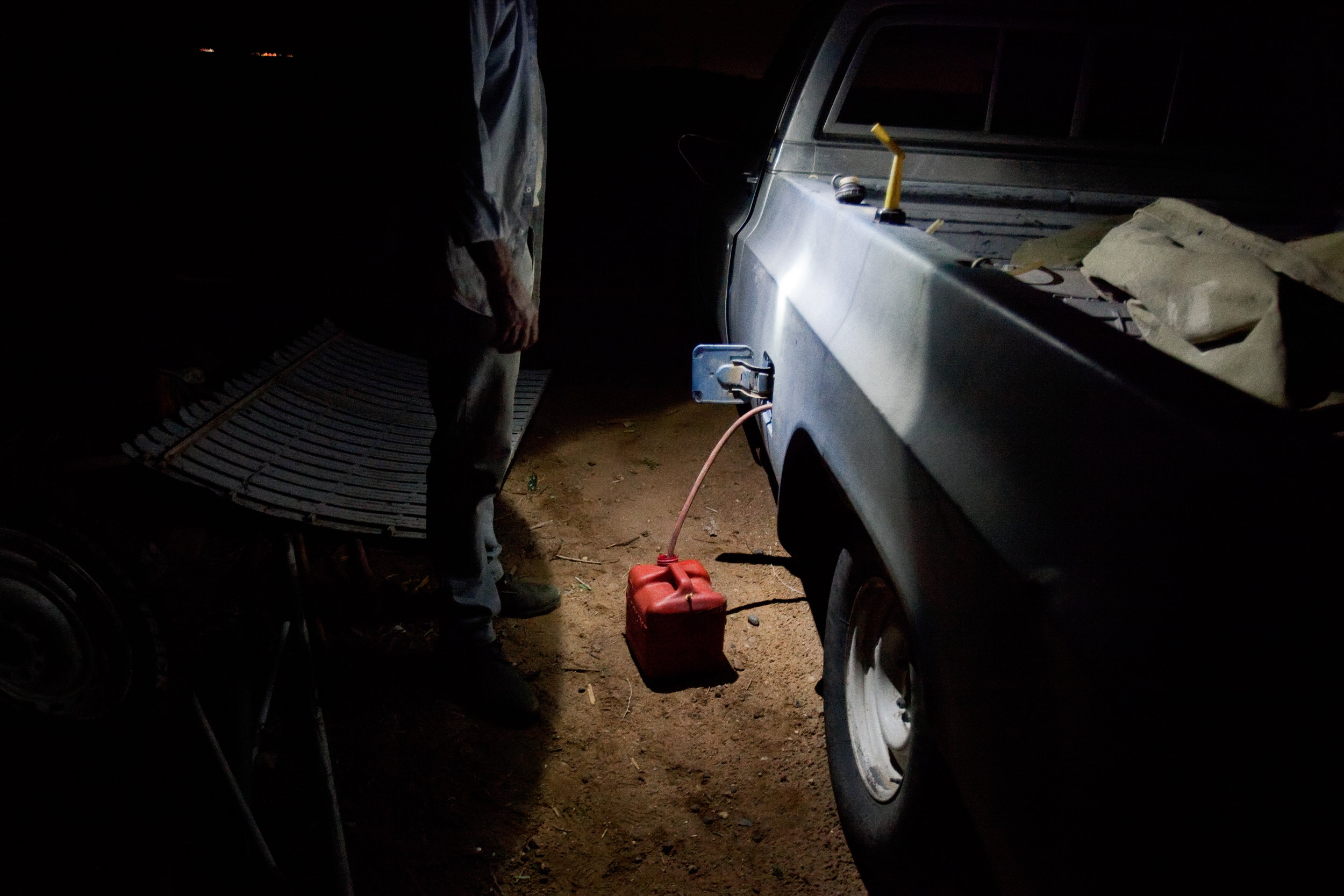  A man siphons gasoline out of his truck so that he can use it to power a generator for a couple of hours in his trailer in Pajarito Mesa, New Mexico, USA on May 28, 2010. 