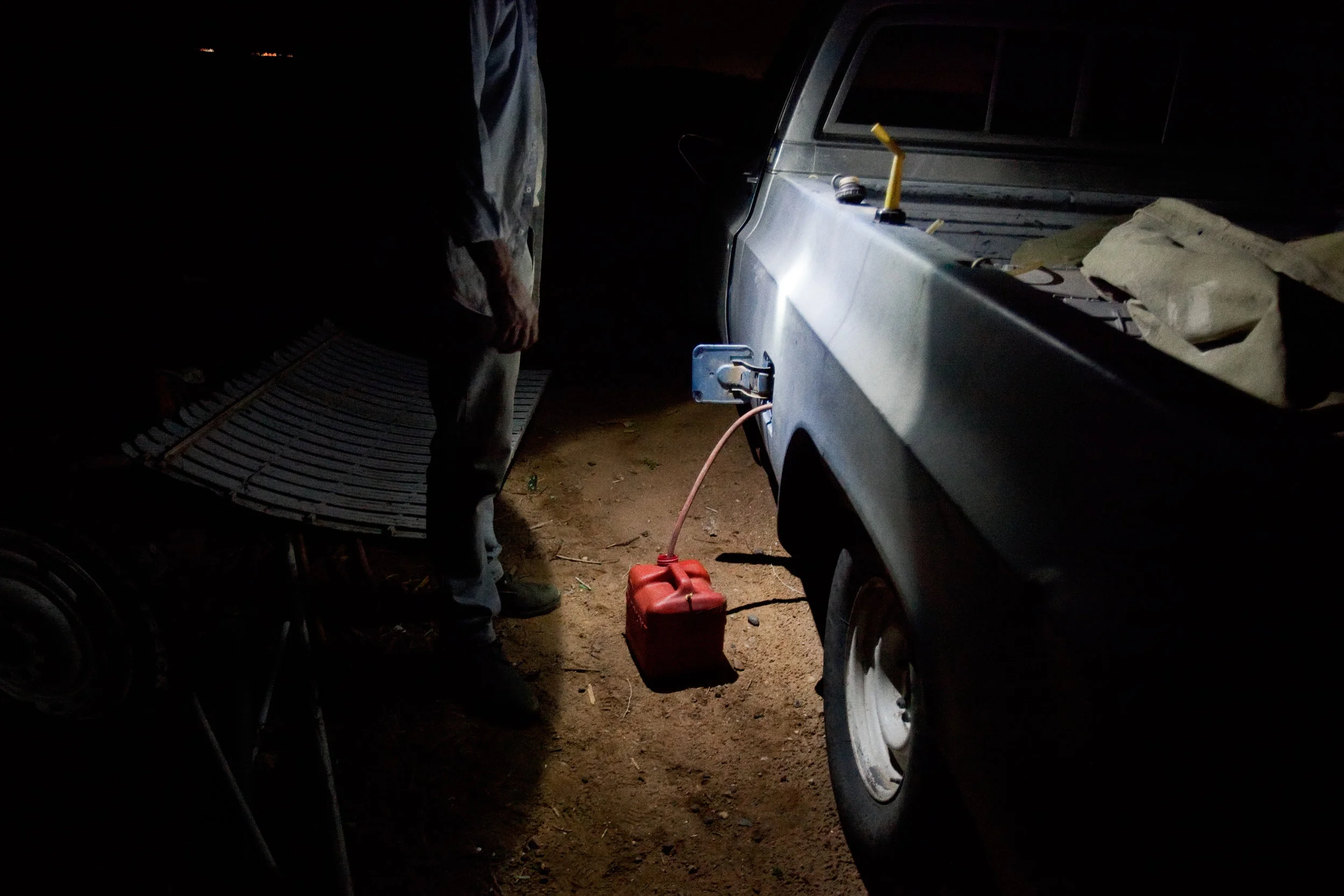 A man siphons gasoline out of his truck so that he can use it to power a generator for a couple of hours in his trailer in Pajarito Mesa, New Mexico, USA on May 28, 2010.