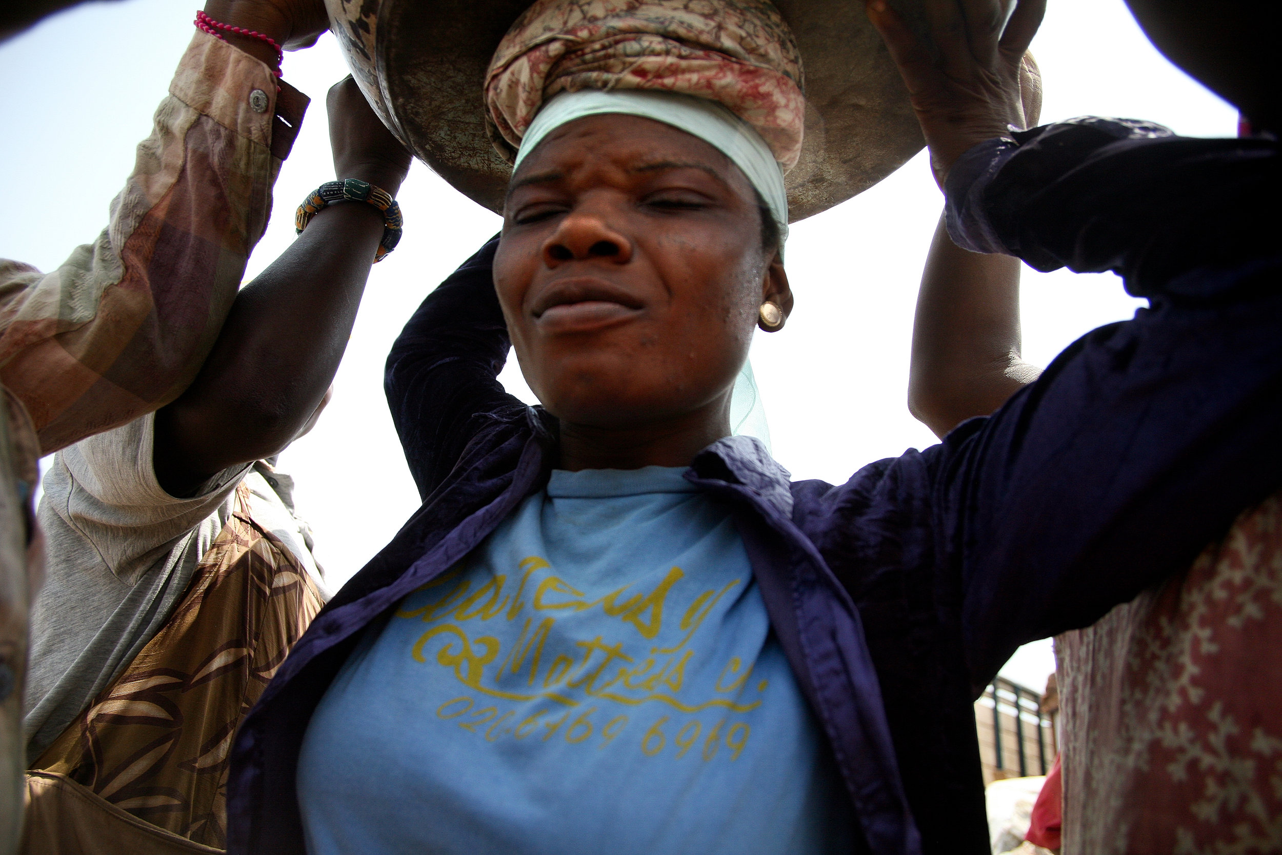  Lamisi lifts a load of yams onto her head in Agbogblushie Market in Accra, Ghana on Feb, 13, 2009. "At the end of the day, your whole body will be paining you," she says of the work. 