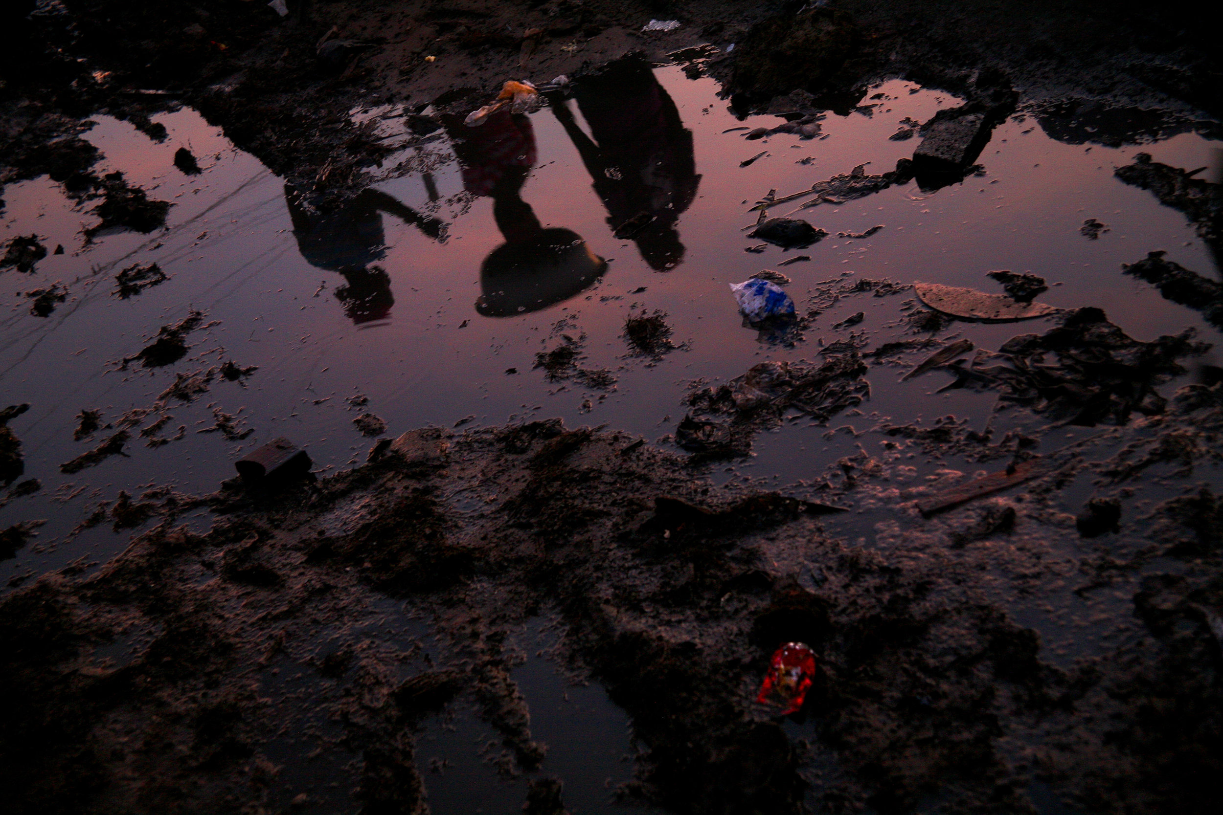  Kayayo girls reflected in the muddy pathways of the Old Fadama slum after a rainstorm in Accra, Ghana on April 14, 2009. The area has become a haven for northerners in the capital city, and each northern tribe has a small neighborhood of shacks and 