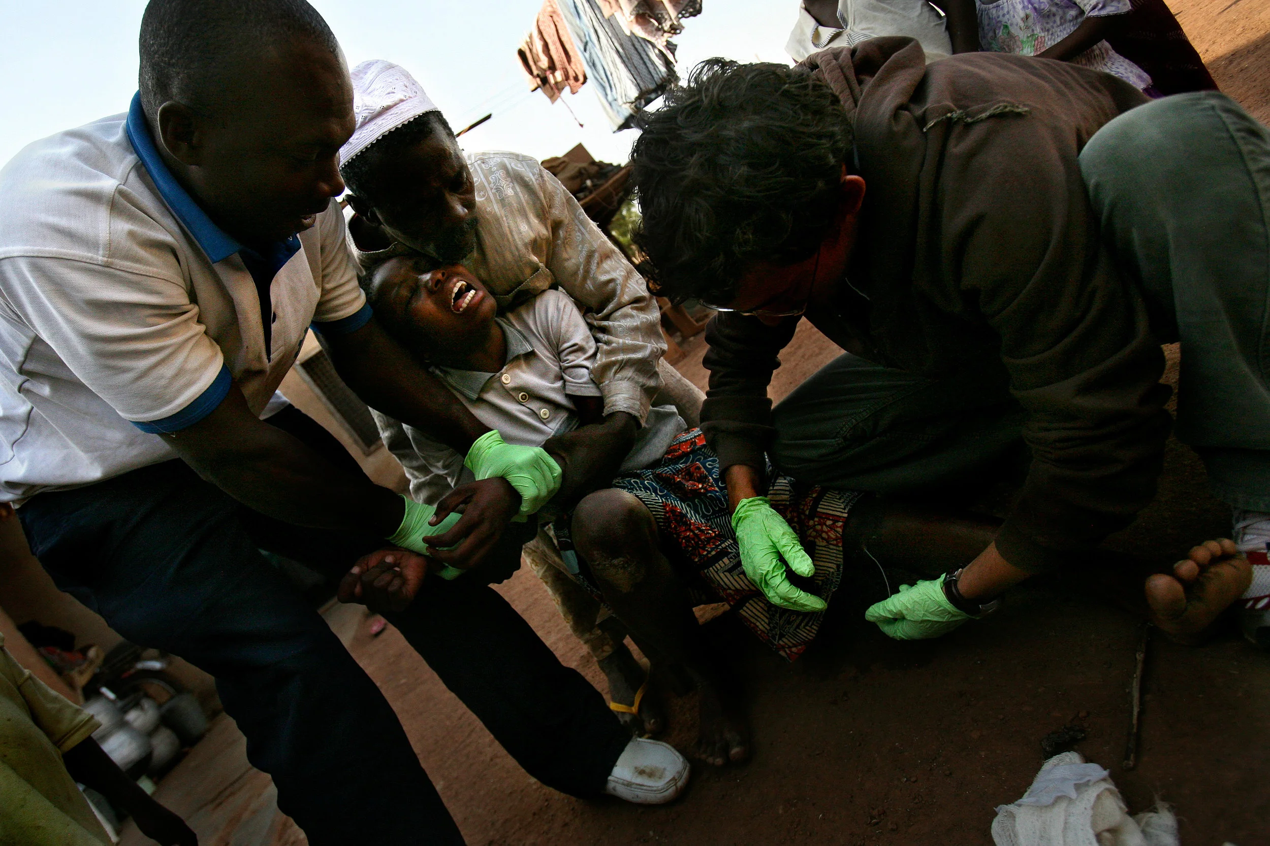 Mariam Inusa, 15, cries out in pain as health workers pull on the Guinea worm in her leg, attempting to remove it, at her home in Savelugu, Northern Region, Ghana on Jan. 26, 2008. The worm in Mariam's leg was finally pulled out after several days of bandaging. Family members and health workers had to hold Mariam still so that they could pull on the worm without fear of Mariam jerking her leg away and breaking the worm.