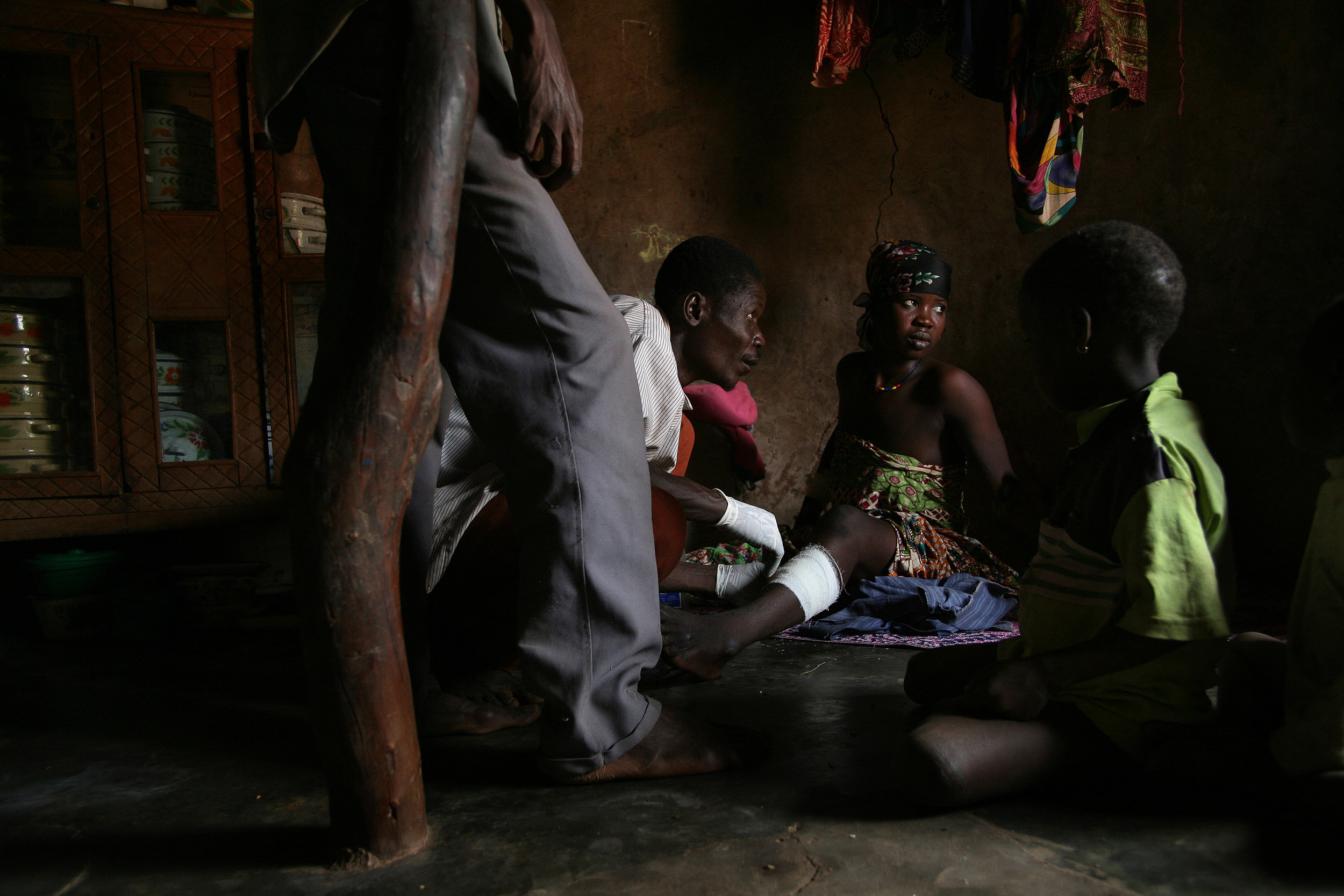  Health worker Abukari Memunatu, center, bandages a woman with Guinea worm disease in the woman's home in Kanfehyili, Northern Region, Ghana on Jan. 24, 2007. Pain in the woman's leg caused by an emerged Guinea worm made it difficult for her to walk,