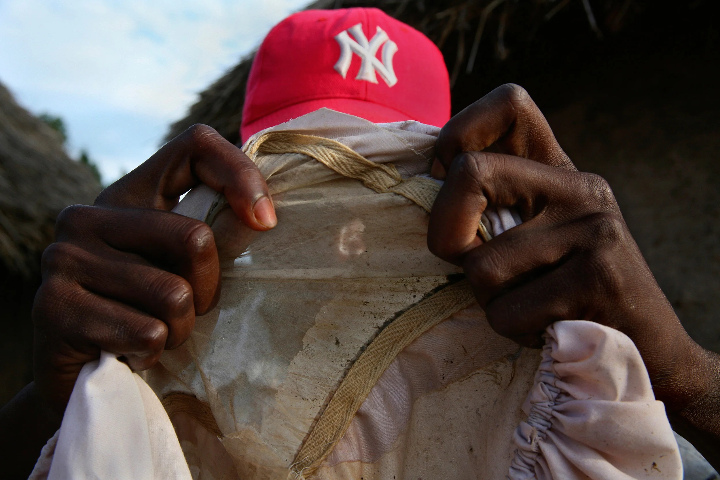Sualey, a Ghanaian National Health Service Volunteer, examines a cloth Guinea worm filter in a home in Wantugu, Ghana, during a routine house-to-house filter inspection on Aug. 15, 2007. A simple cloth filter is enough to remove Guinea worm from drinking water, but house-to-house health education is necessary to make sure people are using the filters properly.