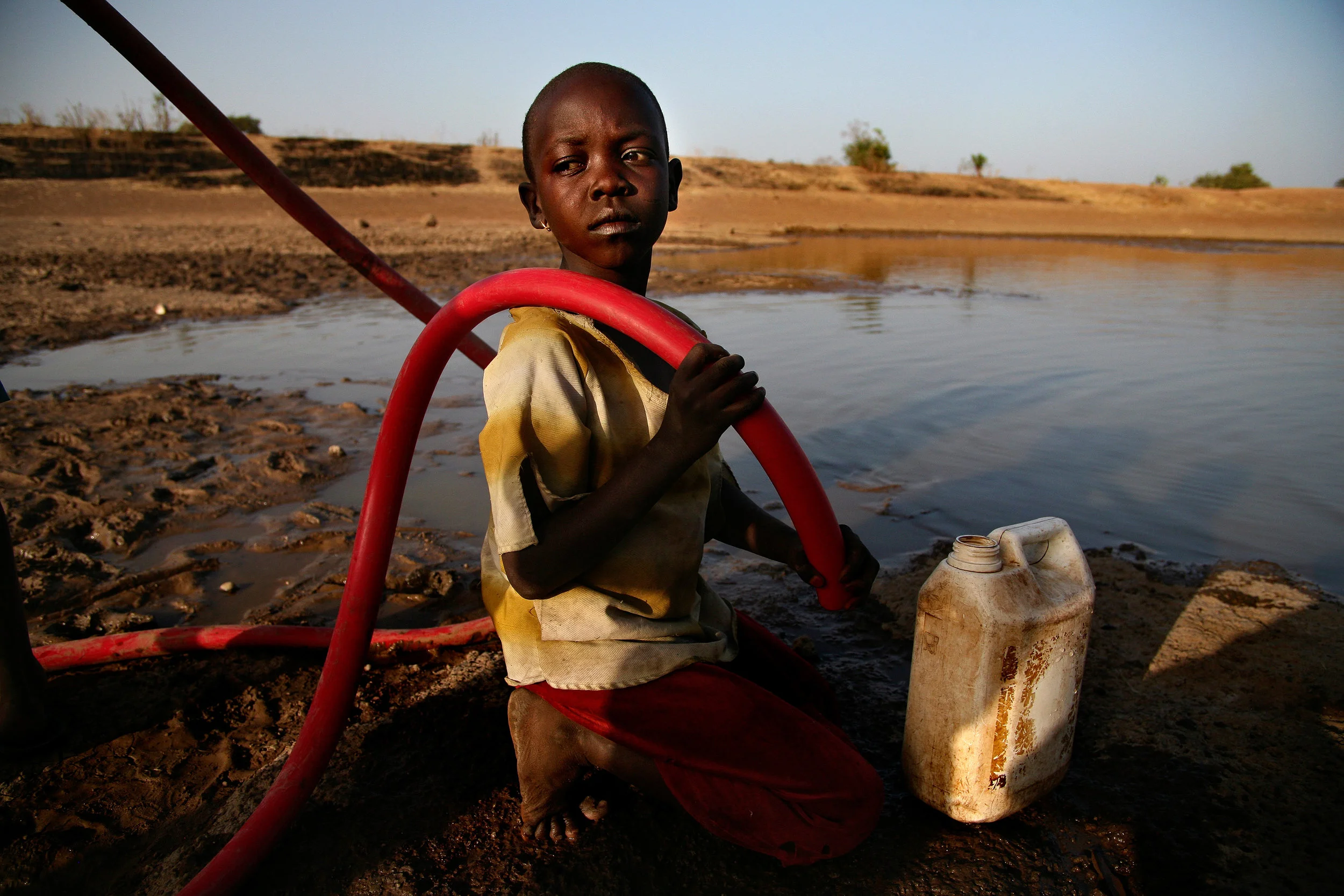A young girl waits for water to flow from a tube being pumped out of Difibihini Dam in Savelugu, Ghana on Jan. 25, 2008. In addition to possibly being contaminated with Guinea worm, dam water is the potential cause for other water-born illnesses. The dam is shared with livestock, including cattle, which wade and defecate in the water.