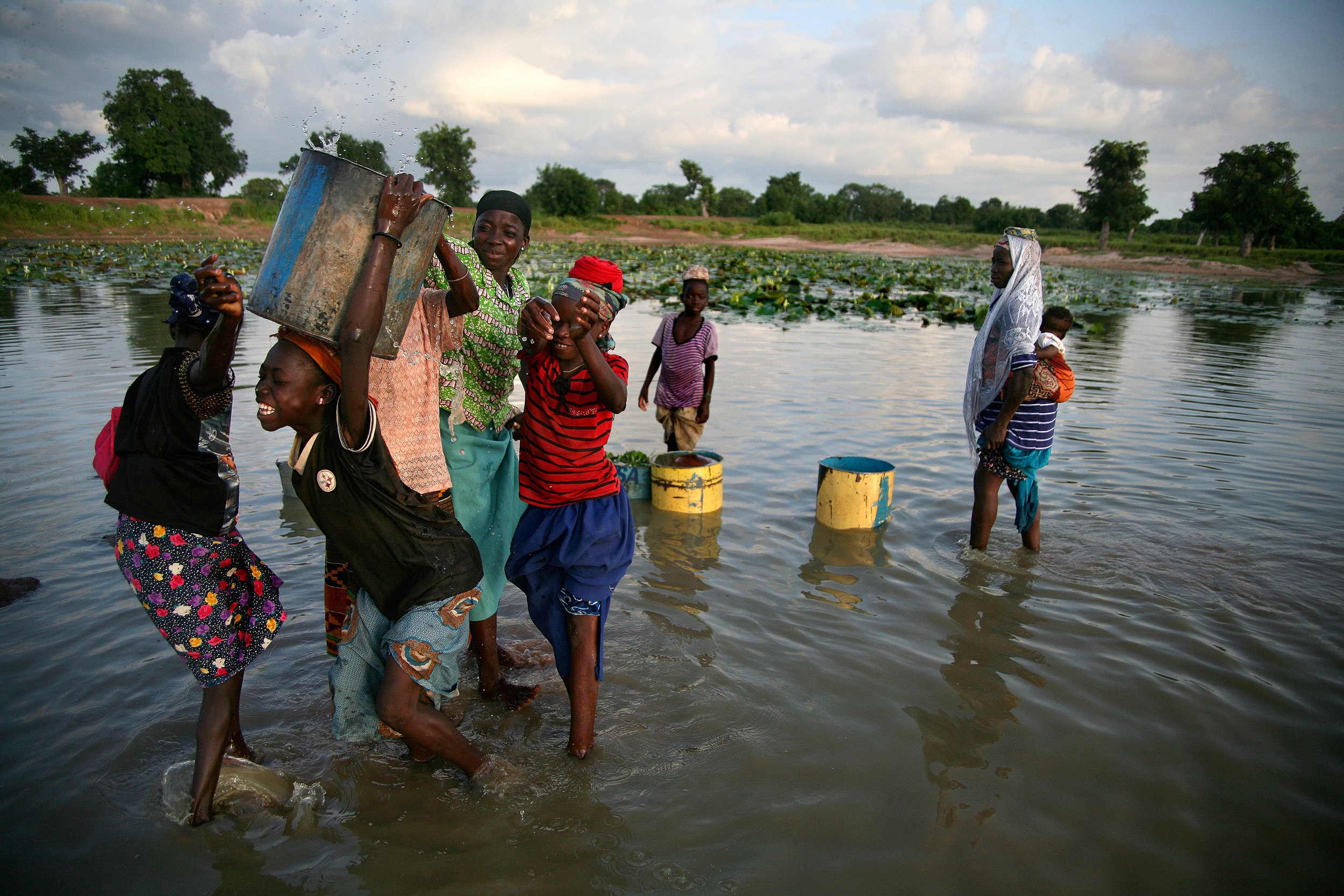  Girls wade into a reservoir in Wantugu, Ghana to fetch water on Aug. 18, 2007. 