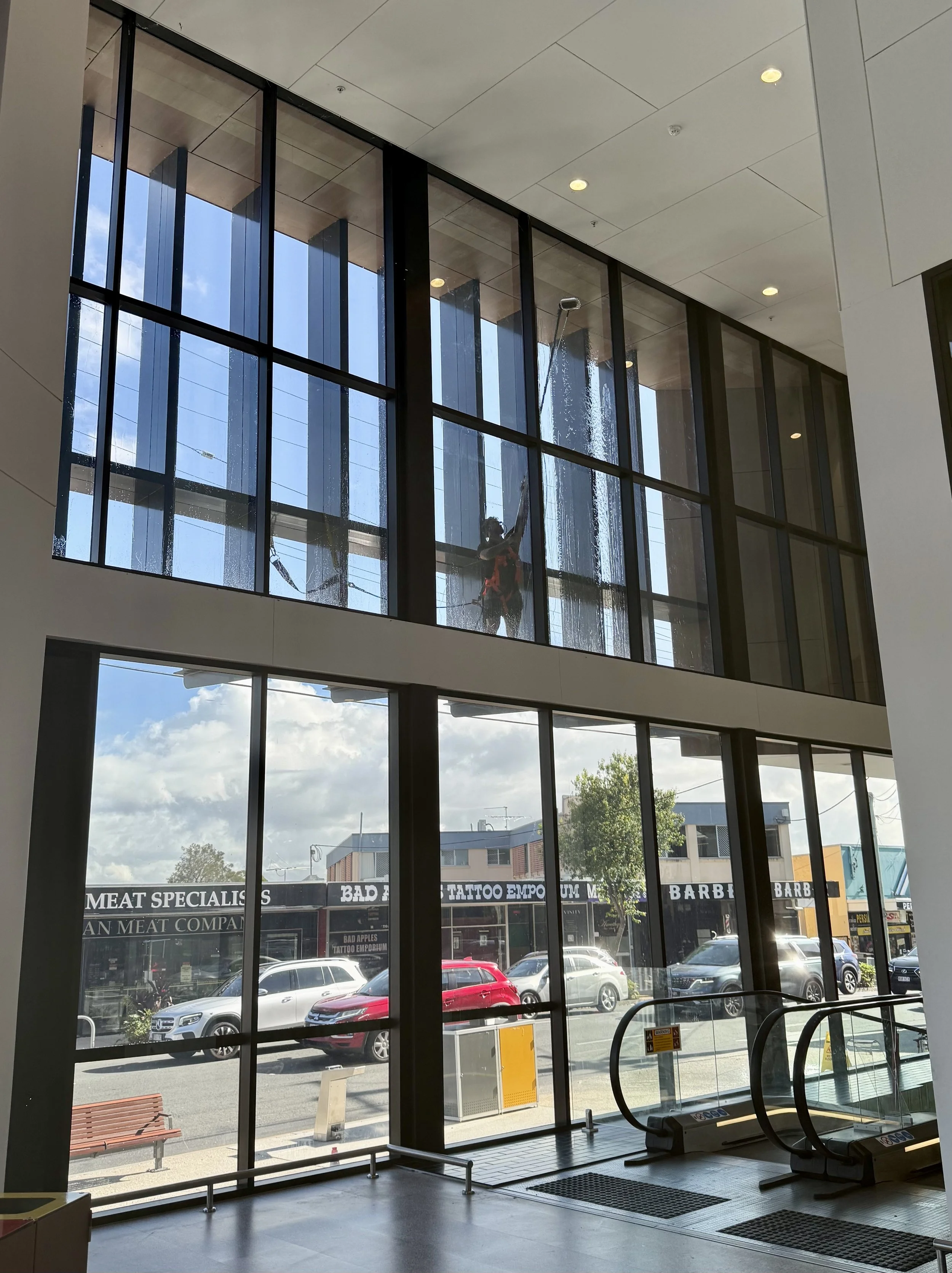 professional commercial window cleaner in Toowong cleaning a large and difficult set of windows on the outside