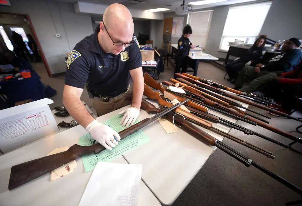 Detective Josh Kyle examines a rifle brought in during a gun buy-back at the New Haven Police Academy in New Haven on December 16, 2017.