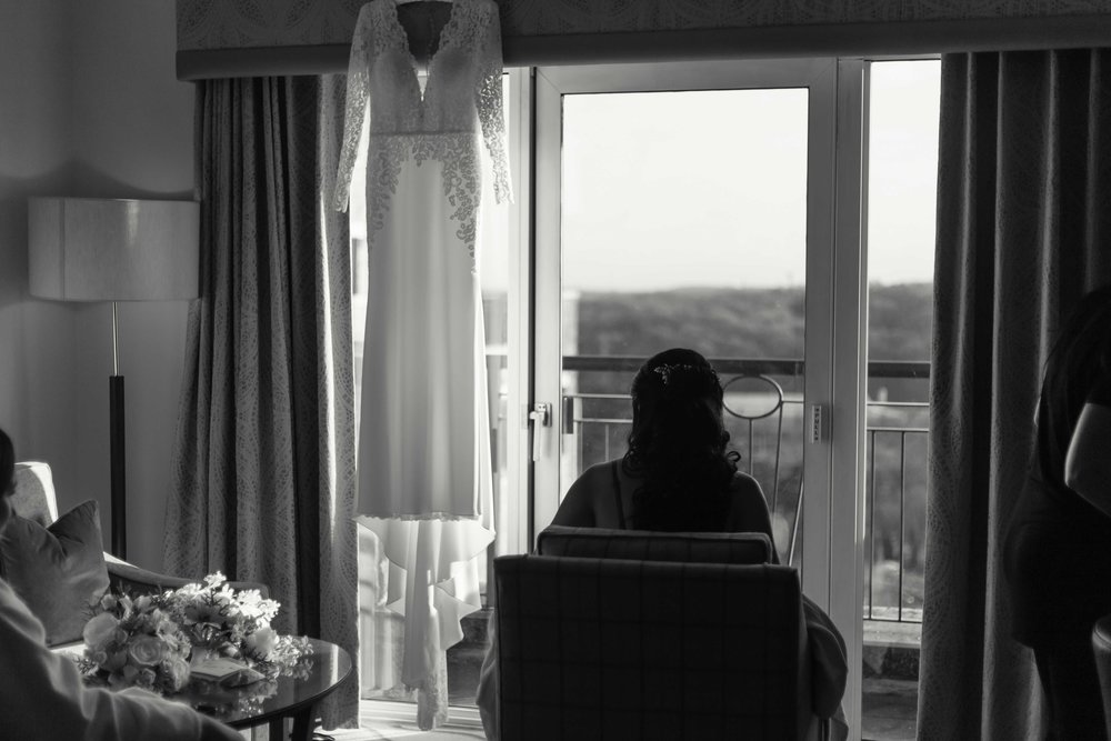 Black and white photograph of bride sitting and looking out of window