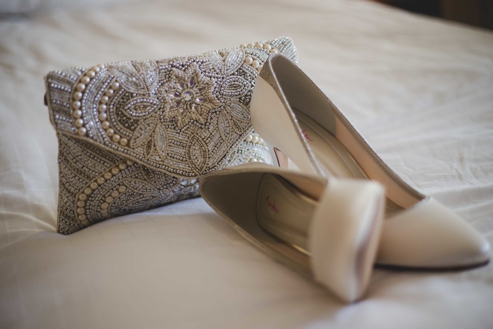 Close up photograph of brides shoes and handbag