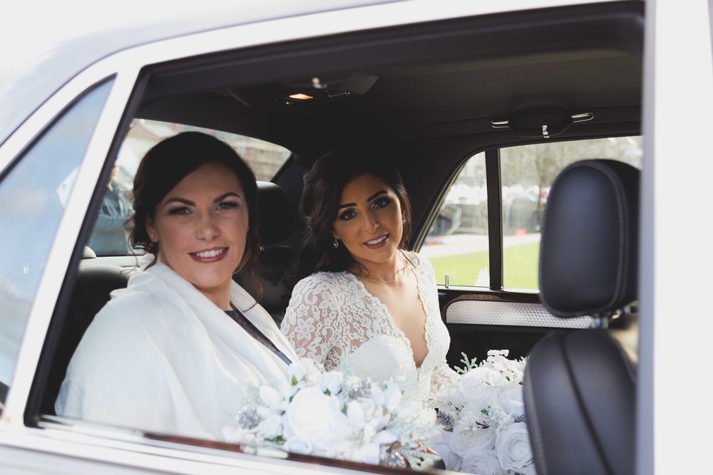 Bride and bridesmaid sat in back of wedding car just before the wedding ceremony