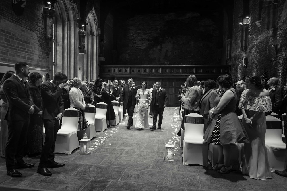 Black and white photograph of the bride walking up the aisle at wedding ceremony at Caerphilly Castle