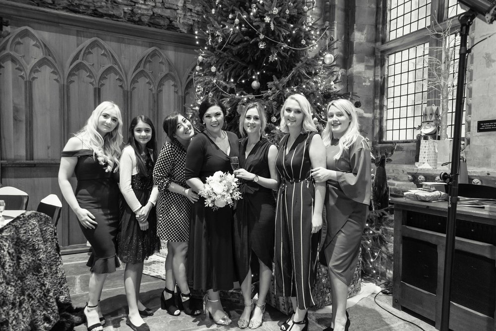 Black and white image of bride with friends next to a christmas tree at Caerphilly Castle