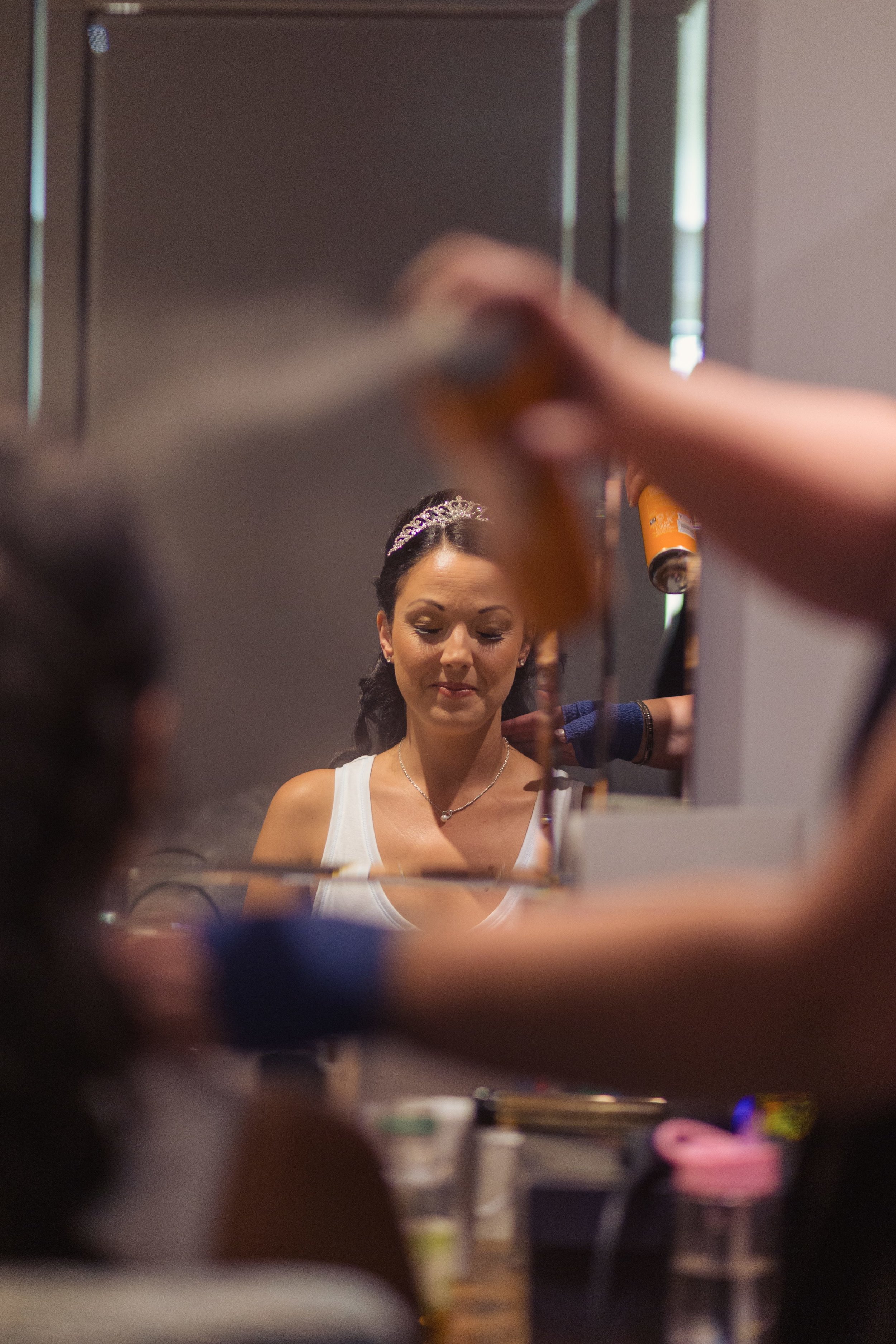 Photograph of a bride at Vale Resort, having her make up applied in front of a mirror