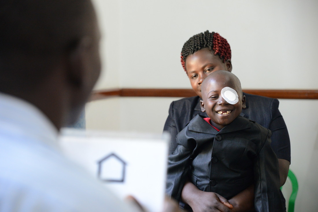 Augustine is smiling and can now open his eyes for the doctor to assess his vision.