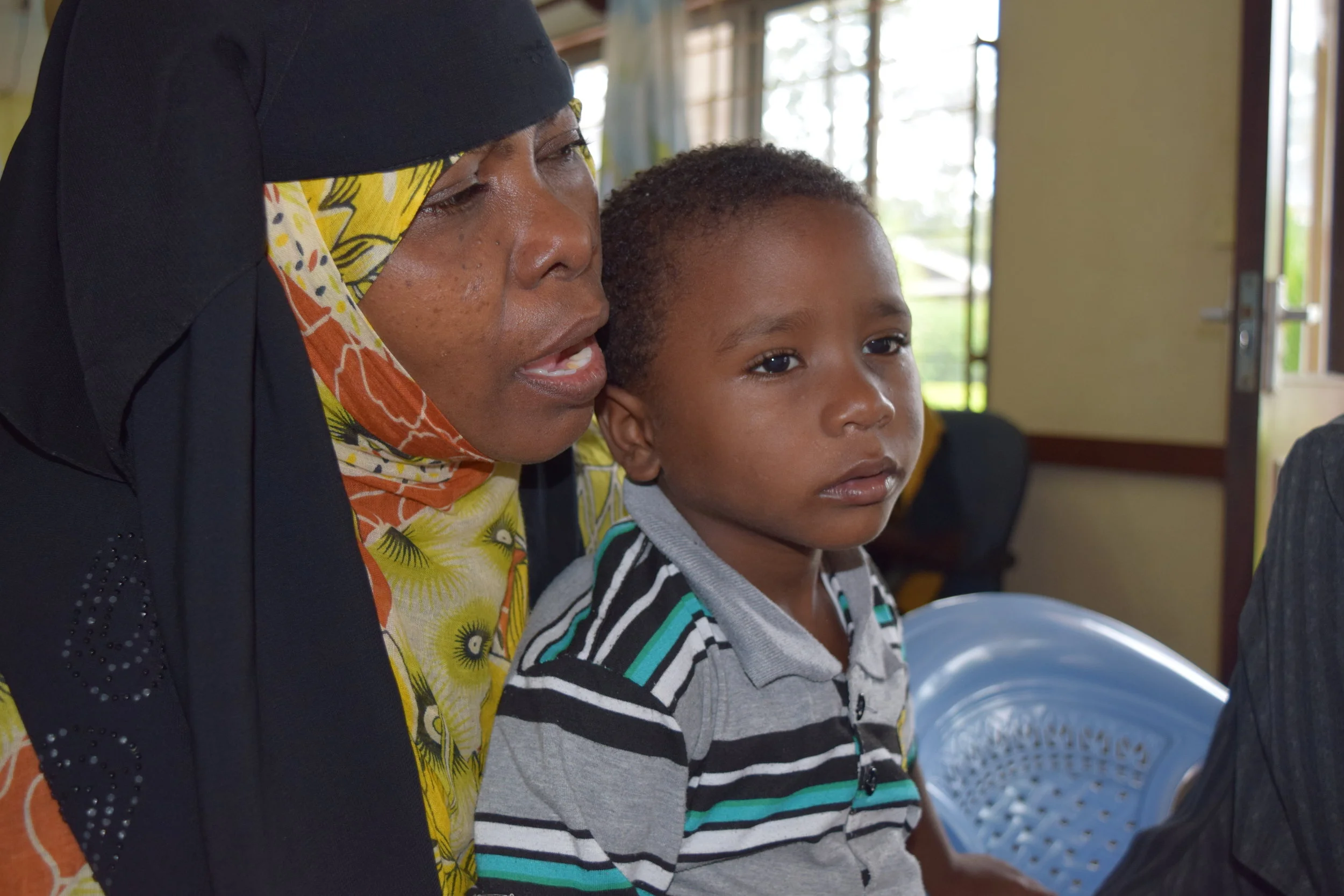 Shakulu, in his mother's arms, looks at the eye test chart.