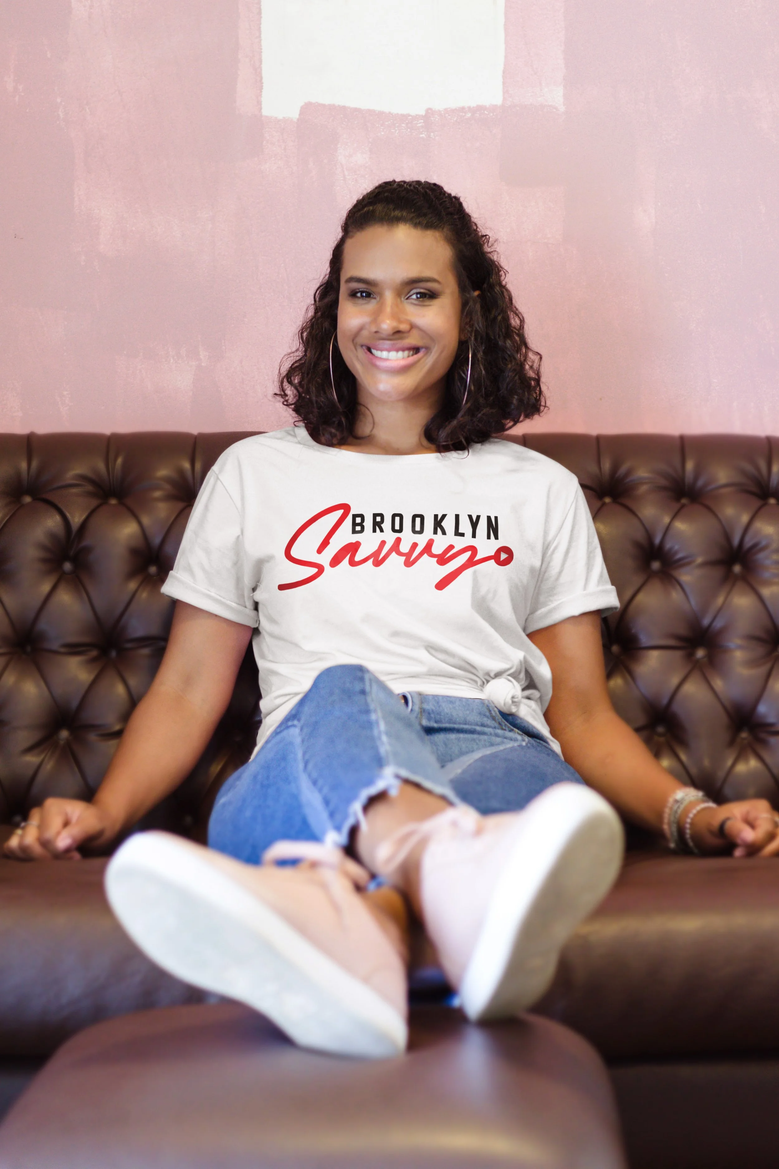 Beautiful Curly Hair Black Young Woman Wearing a Round Neck T-Shirt while Sitting on a Sofa and Smiling.jpg
