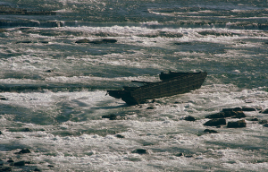 The scow, firmly wedged in between the rocks of the river.