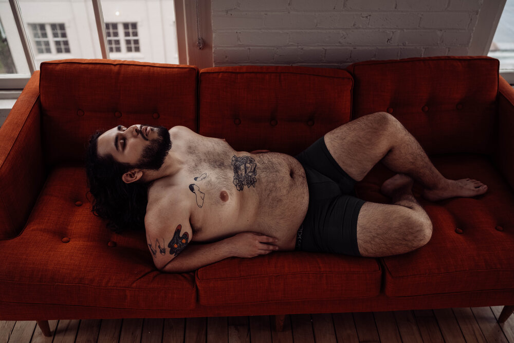 Oklahoma City Male Boudoir man with beard leaning back on couch shirtless with tattoos