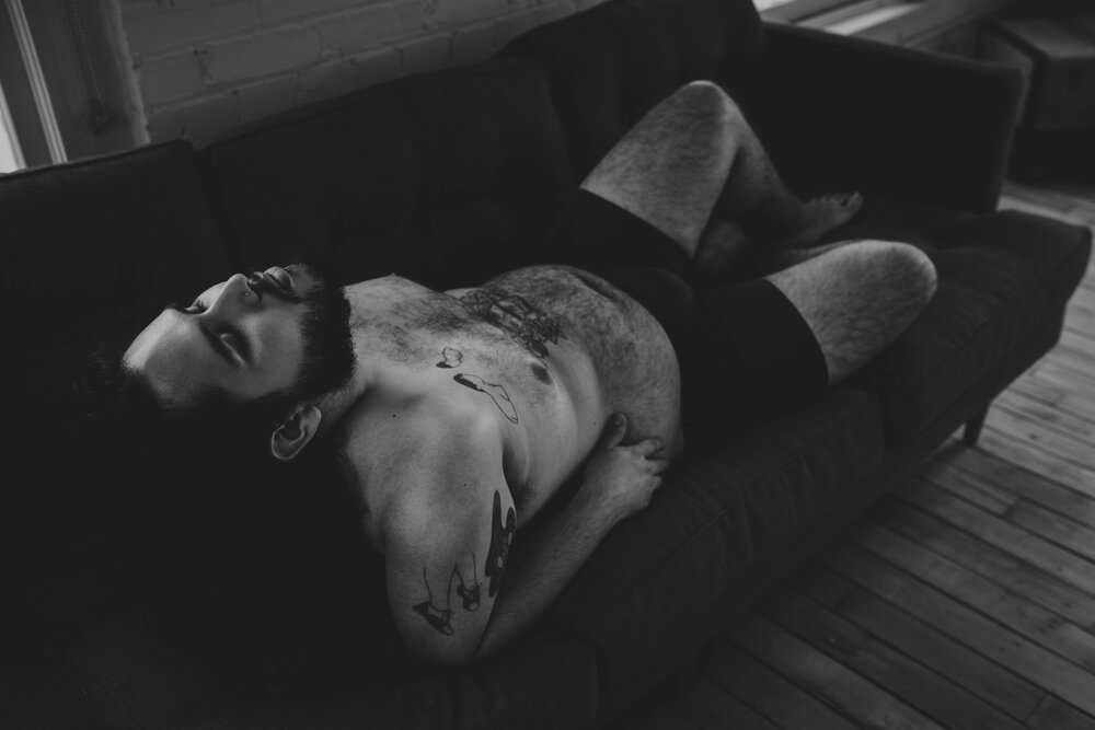 Oklahoma City Male Boudoir black and white portrait of man with beard leaning back on couch shirtless with tattoos