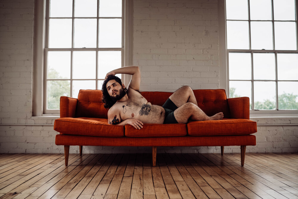Oklahoma City Male Boudoir bearded shirtless man with tattoos posing on orange couch