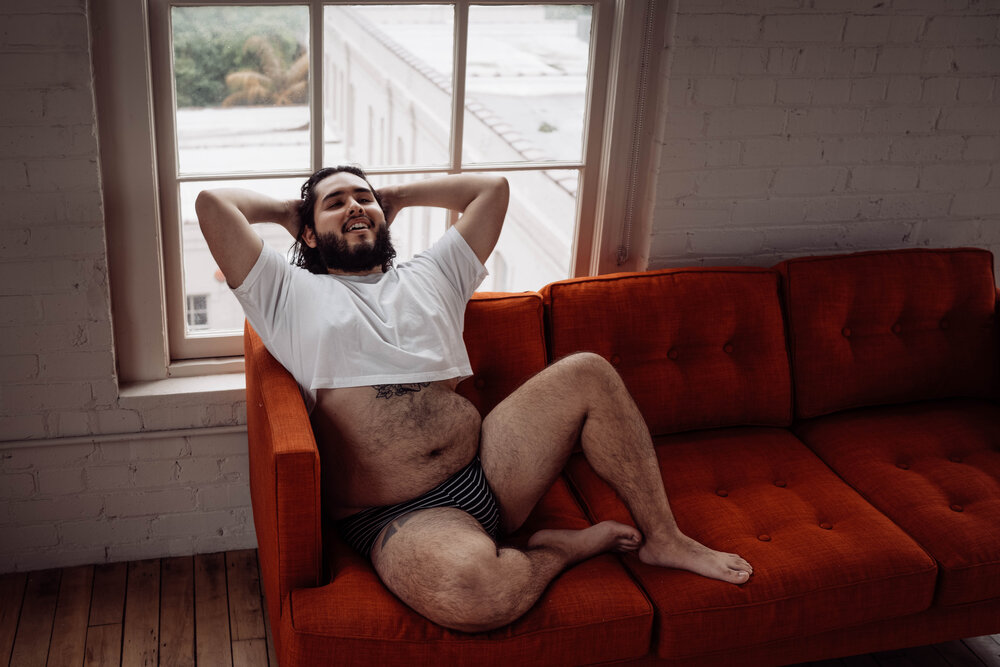 Intimate_Lens_Studio-5.jpgOklahoma City Male Boudoir bearded man in white shirt sitting on orange couch  and laughing