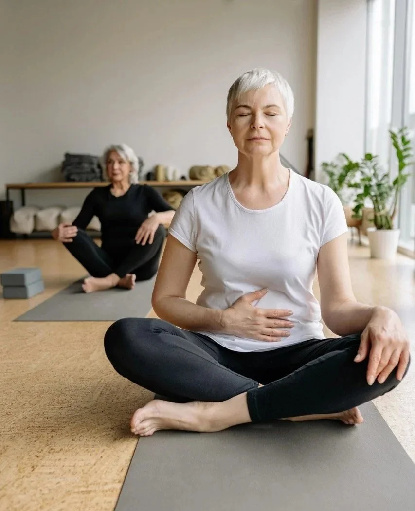 Two older women do yoga in a studio