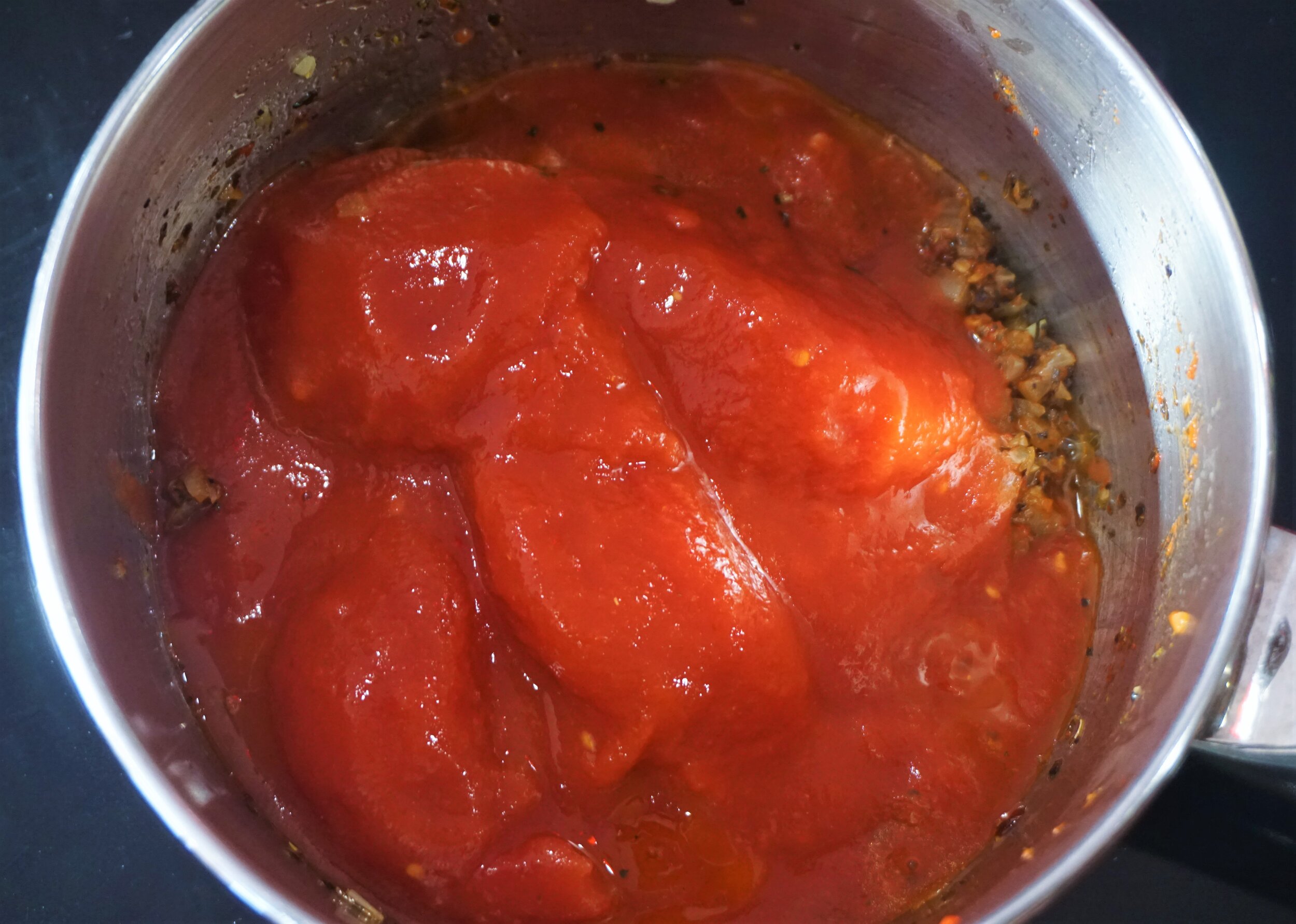 Add the whole tomatoes and gently mash into the rest of the sauce.