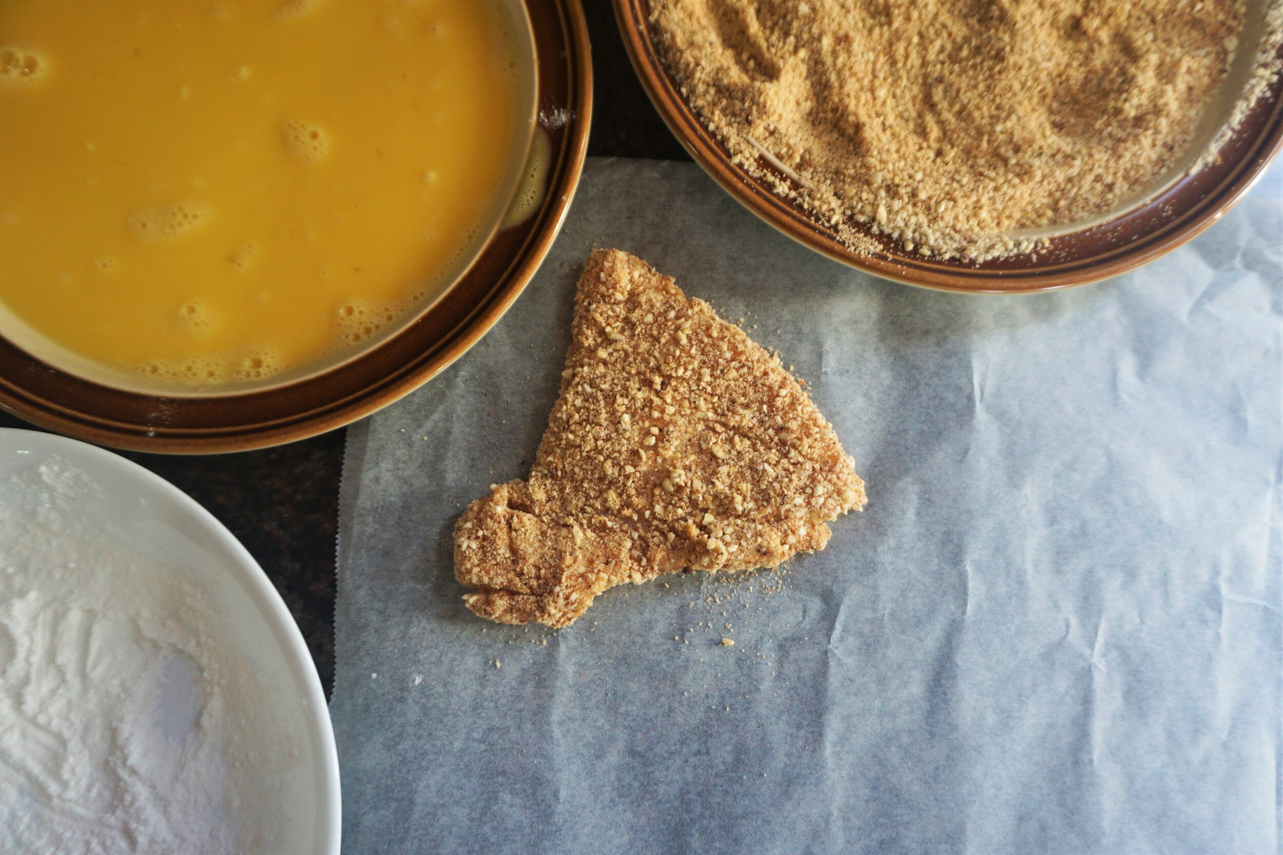 Arrange your flour, egg, and ground almond mixture on plates for easy coating.