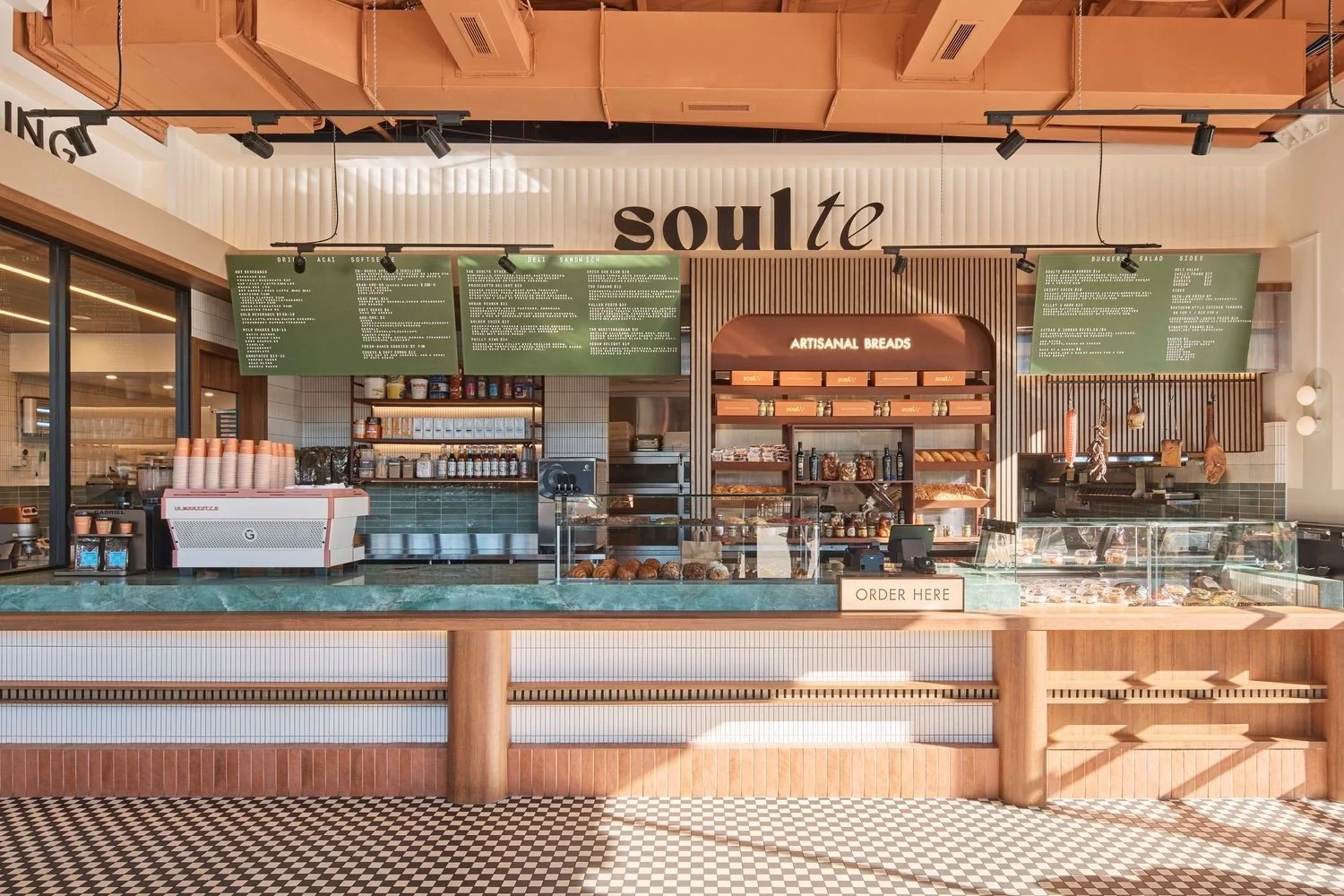 Modern deli counter at Soul te in Minchinbury with a green stone countertop warm wood cladding and artisanal bread display