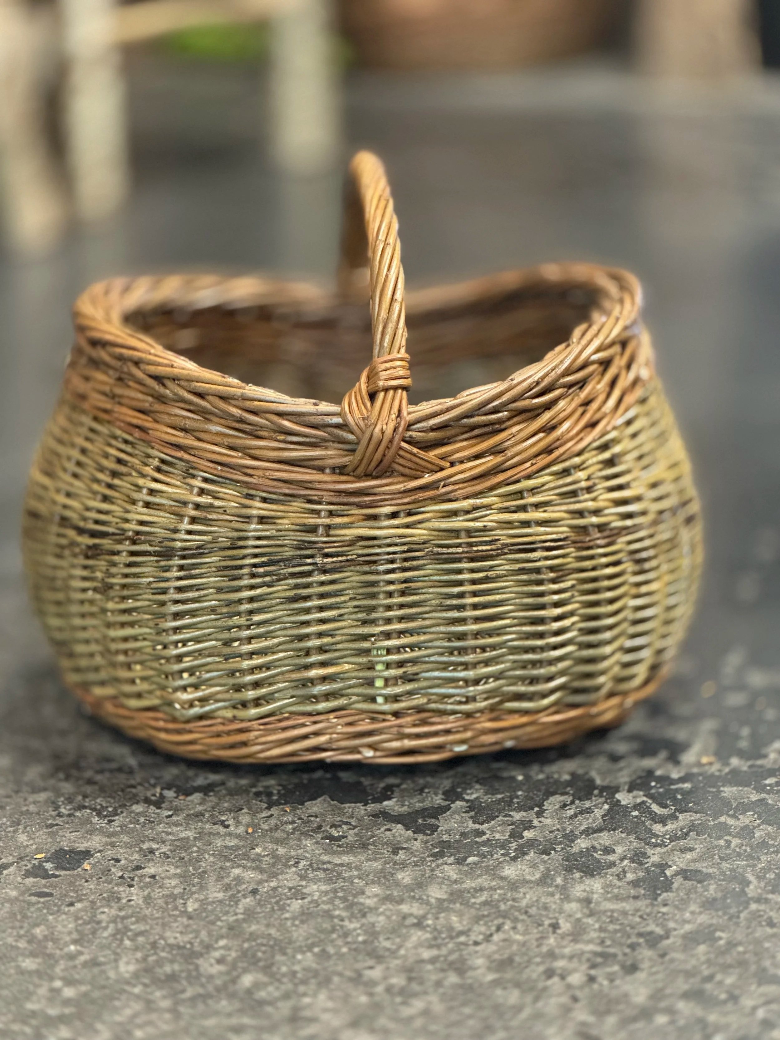 Et lite kurv laget av flettet materiale, plassert på en steinoverflate.