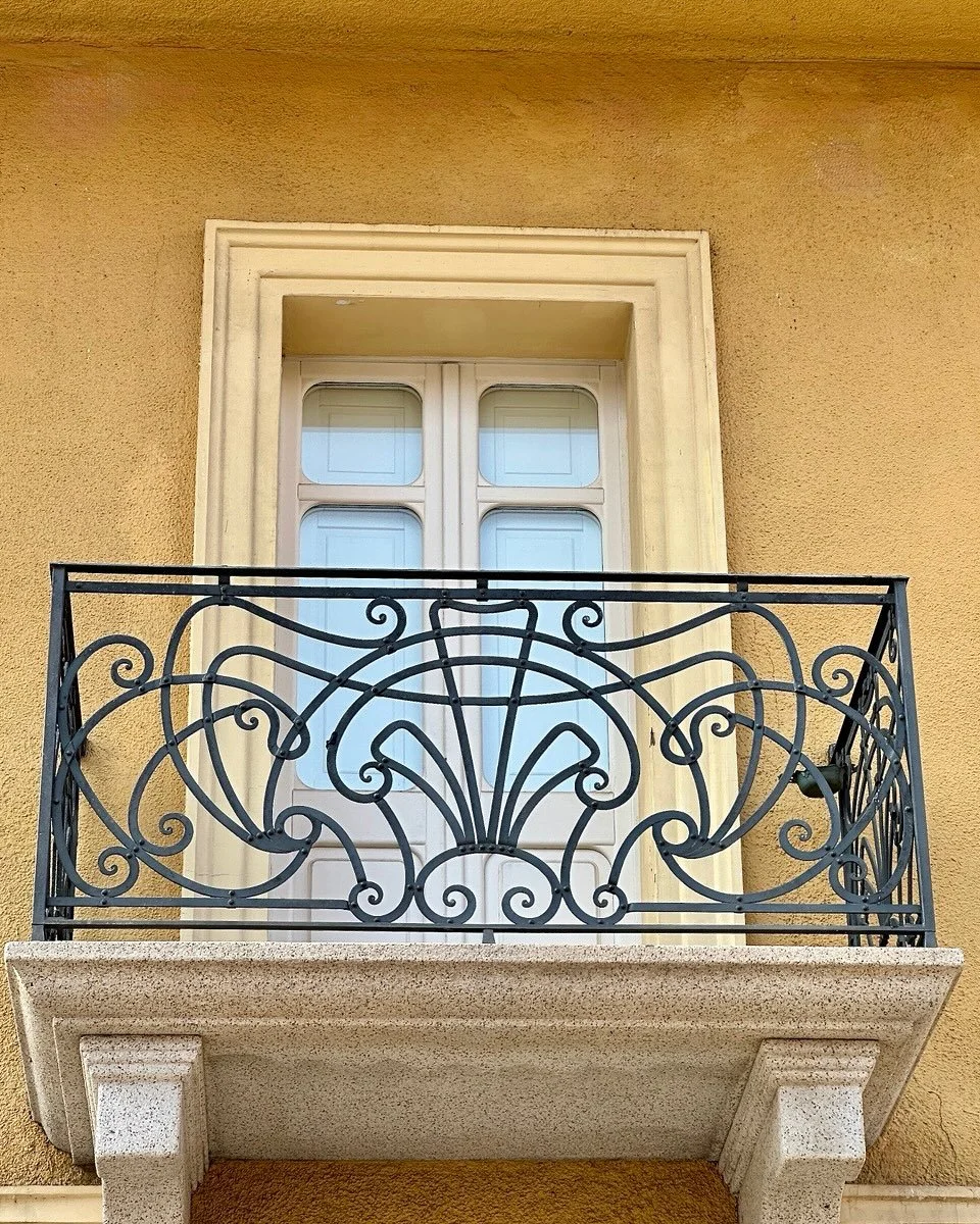Travel Tips Tuesday inspiration from Olbia Sardinia, where the main thoroughfare in the quiet, ancient city center is lined with attractive 3-4 story buildings, painted pale colors and adorned with beautiful ornate metal-railed balconies, each differ